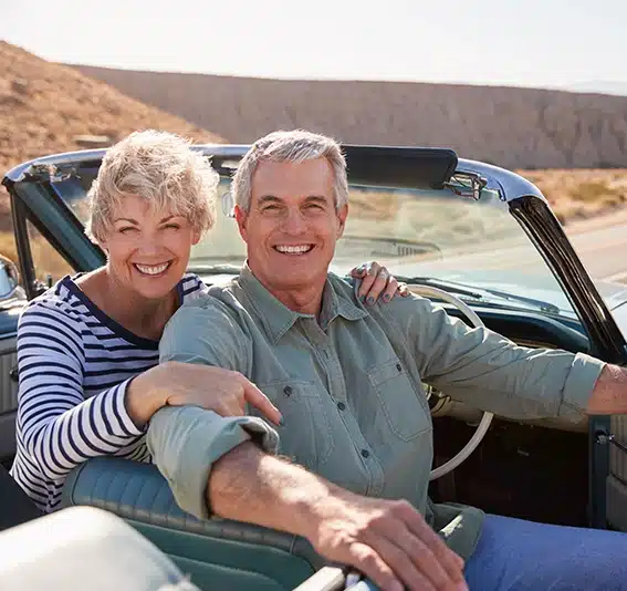 Senior couple smile from open top car