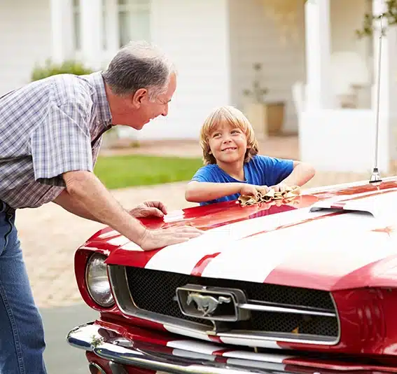 Grandfather with his grandson cleaning a Classic Car