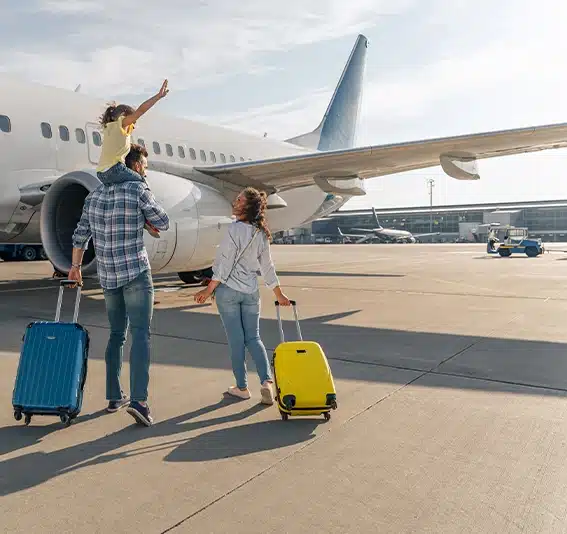 Back view of happy family standing near a large plane with two suitcases outdoor
