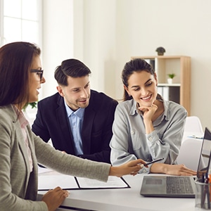 Couple having discussions with a broker while pointing at a laptop