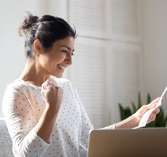 A happy woman with fist up and holding a piece of paper