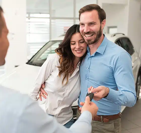 Seller giving car keys to the couple who bought a new car