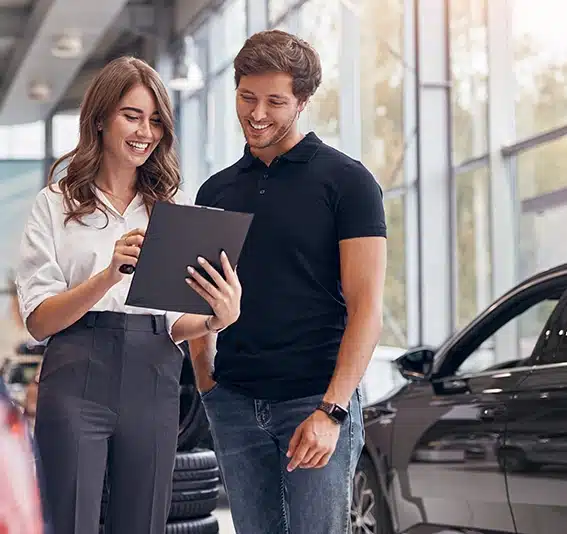 A young woman and man discussing a document while buying a new car