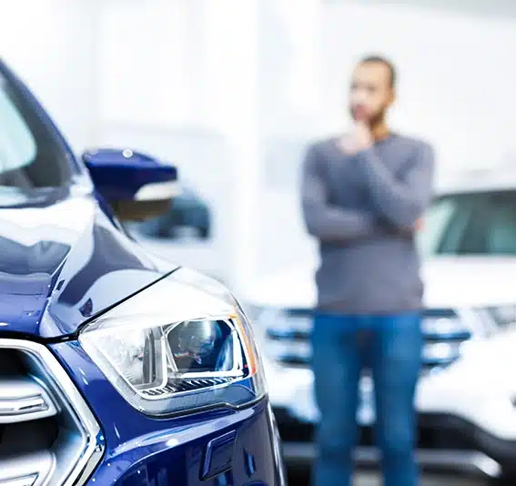 Male customer rubbing his chin thoughtfully choosing a car to buy at the car dealership
