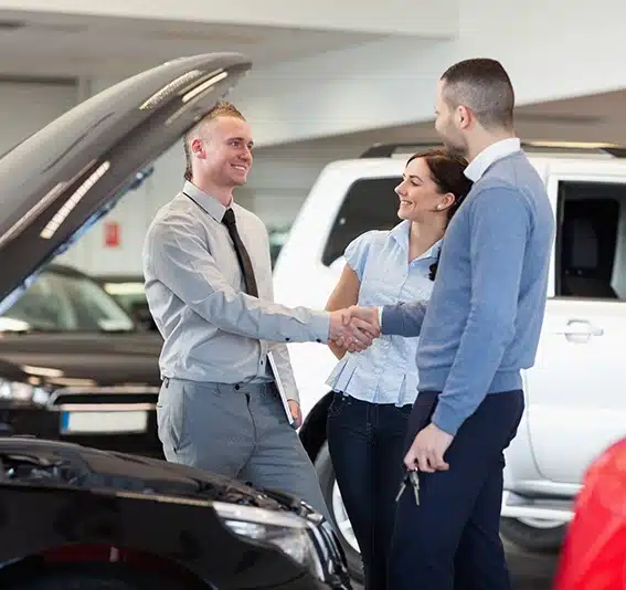 Man shaking hand of a car dealer in front of a car