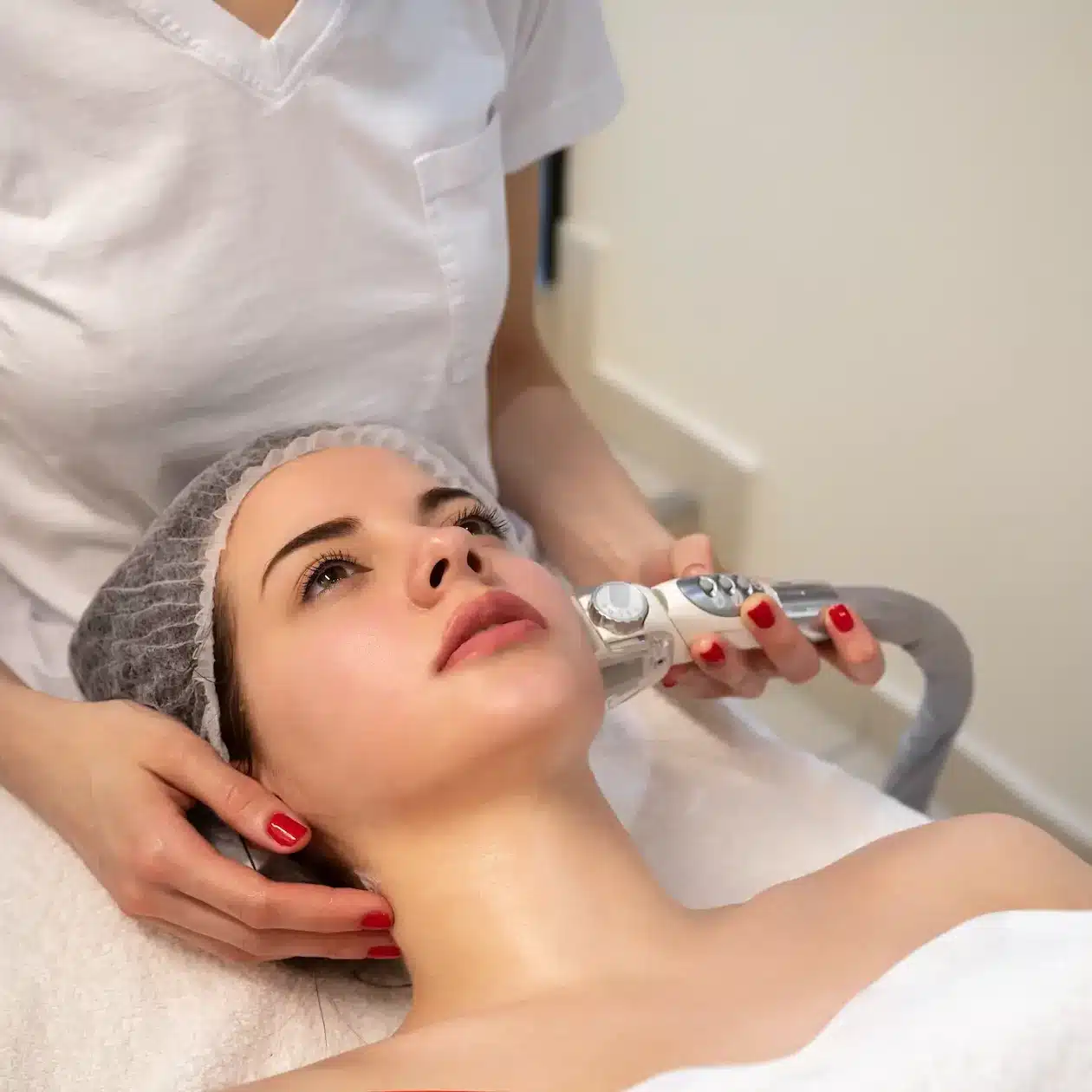 A professional beauty practitioner using a skin treatment machine on a patient
