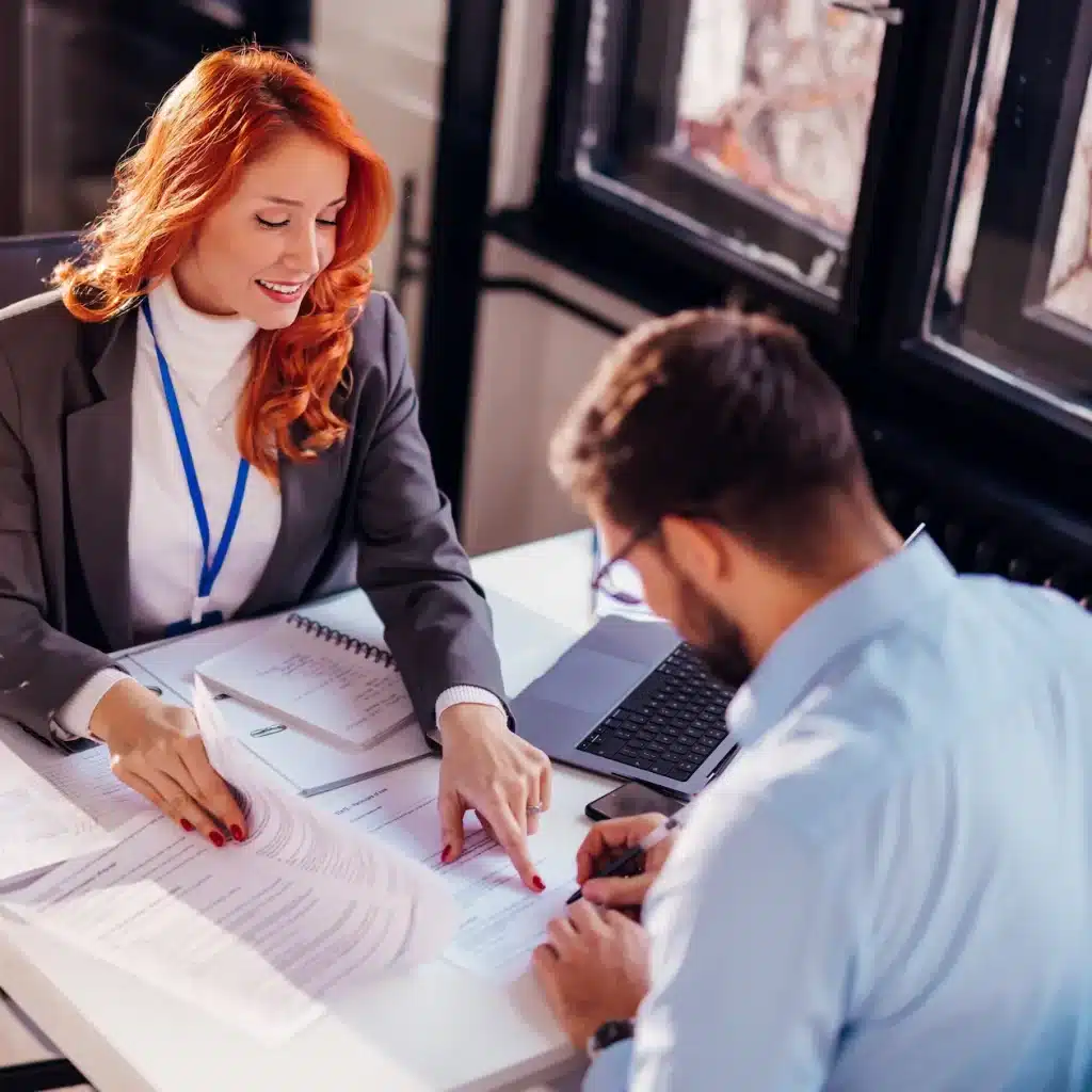 Two business people signing documents for a business purchase