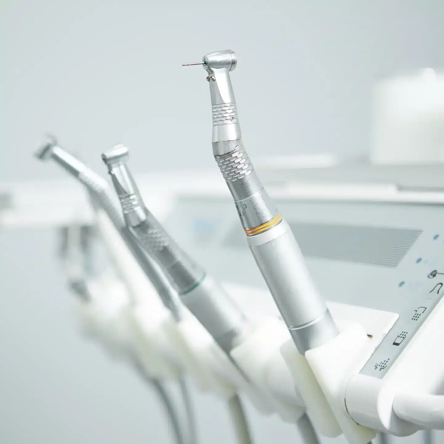 Close up view of dental tools like drill, irrigation, suction in their holders
