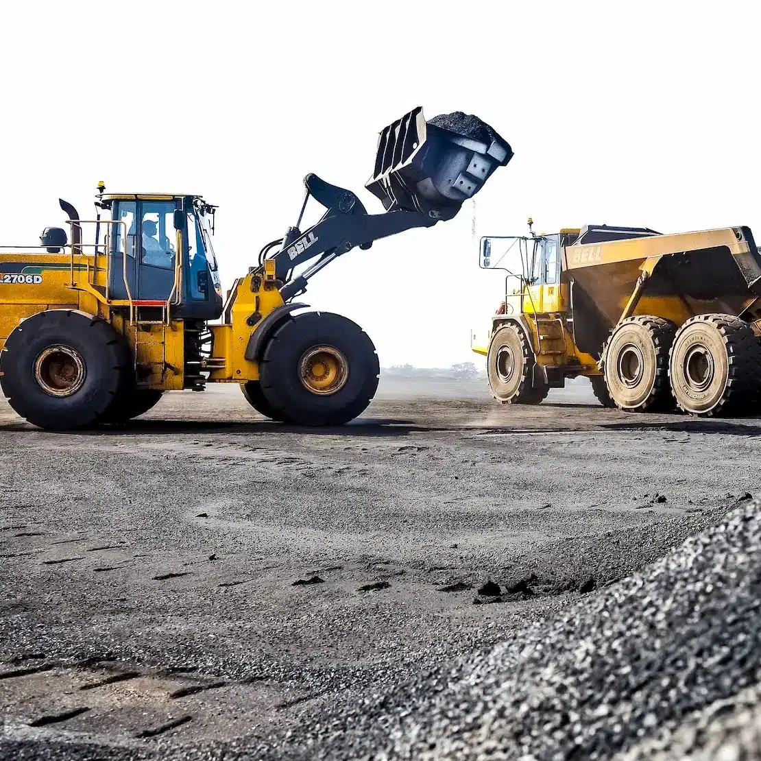 A heavy front end loaded is lifting a bucket full of material towards the heavy tipper