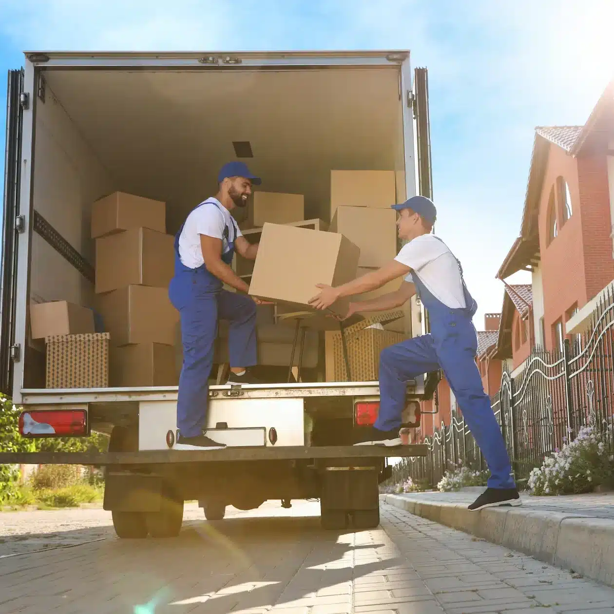 Two delivery men unload boxes from the back of their truck