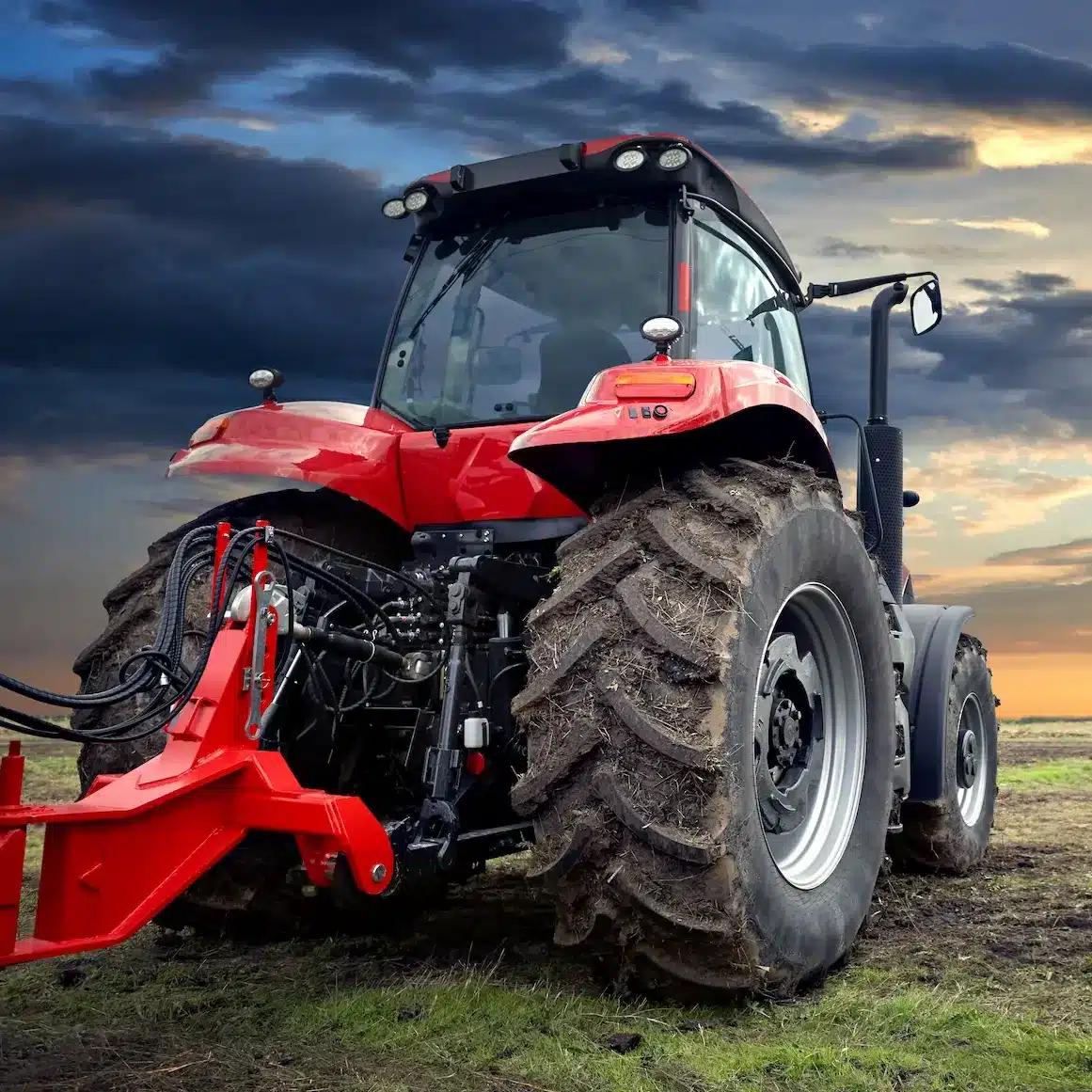 A large new tractor parked on an open field at sunset
