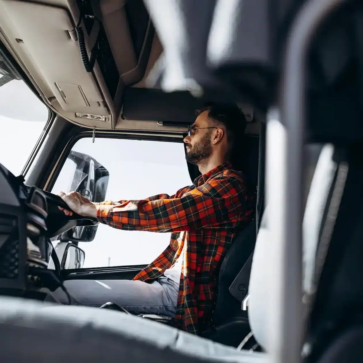 A truck driver sitting in the cab driving down the road