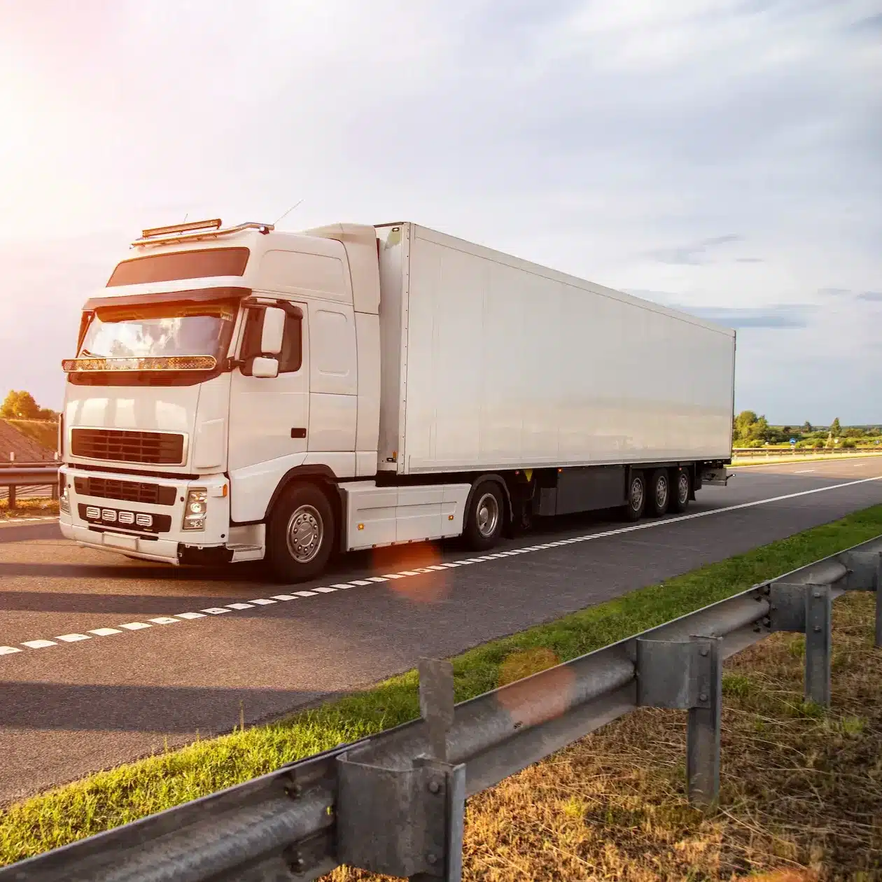 A truck with a large solid side trailer hauling freight down a highway