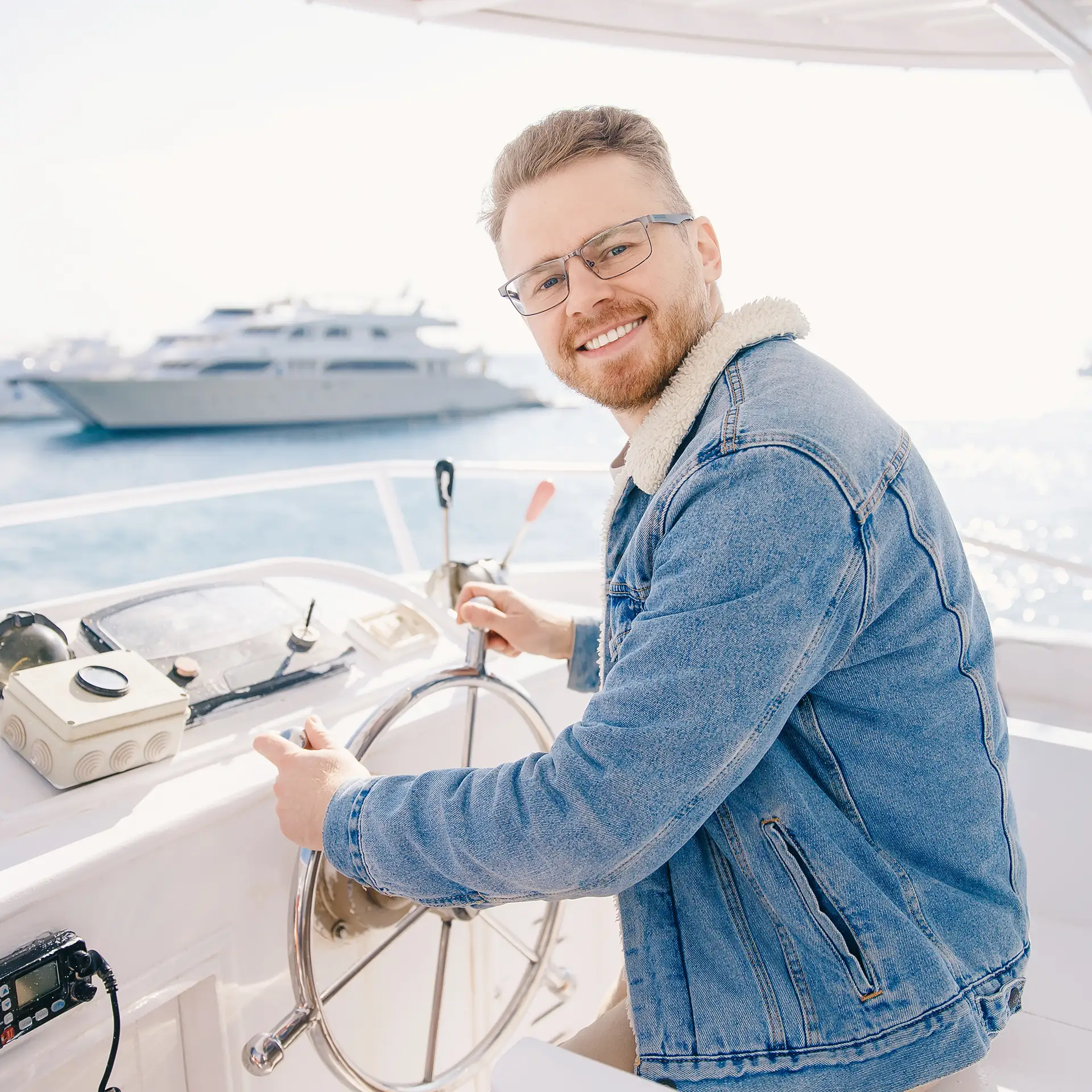 Smiling man holding the helm wheel, enjoying a summer boat trip at sea