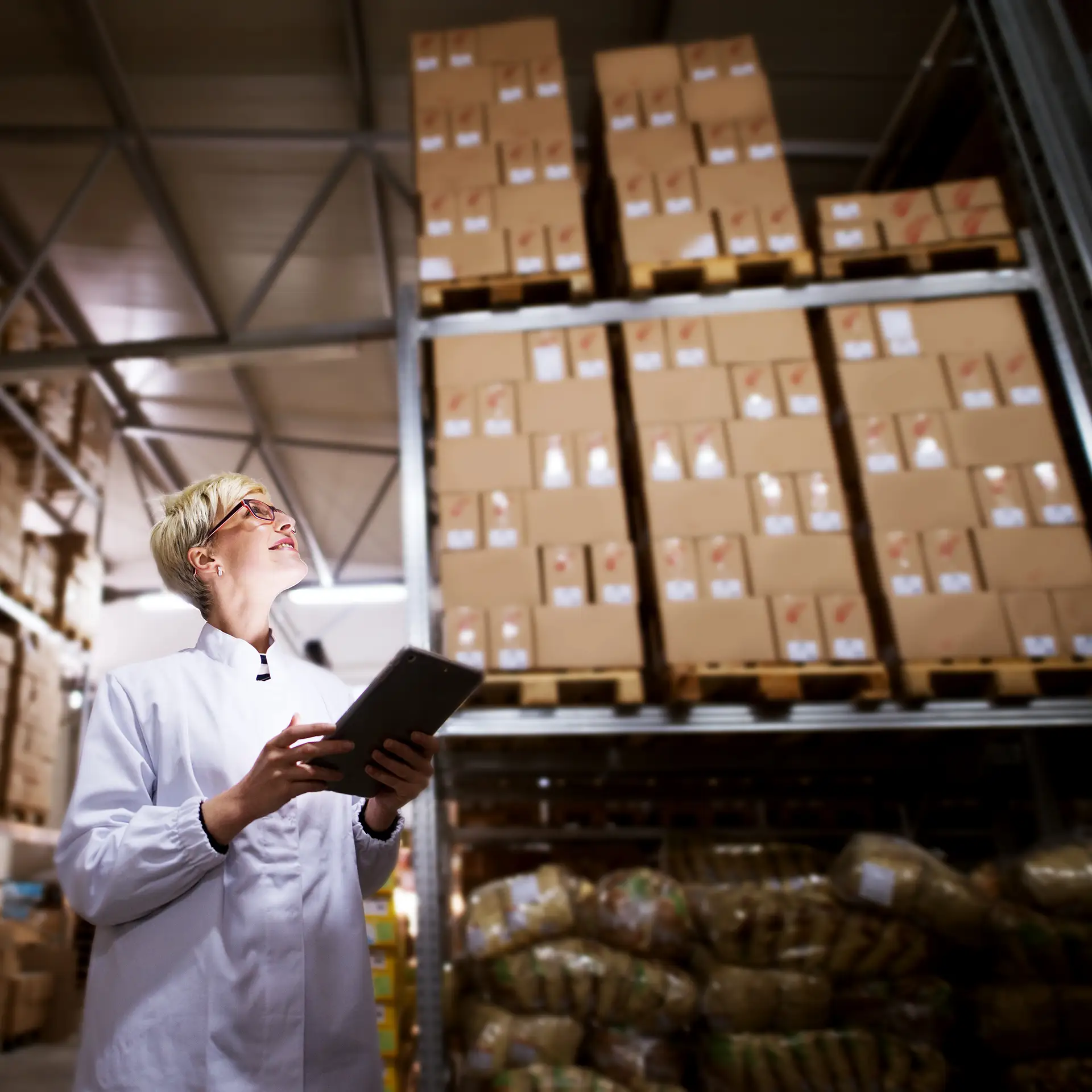 A cheerful female worker is using a tablet to check if the production quota has been achieved in the factory's cargo area