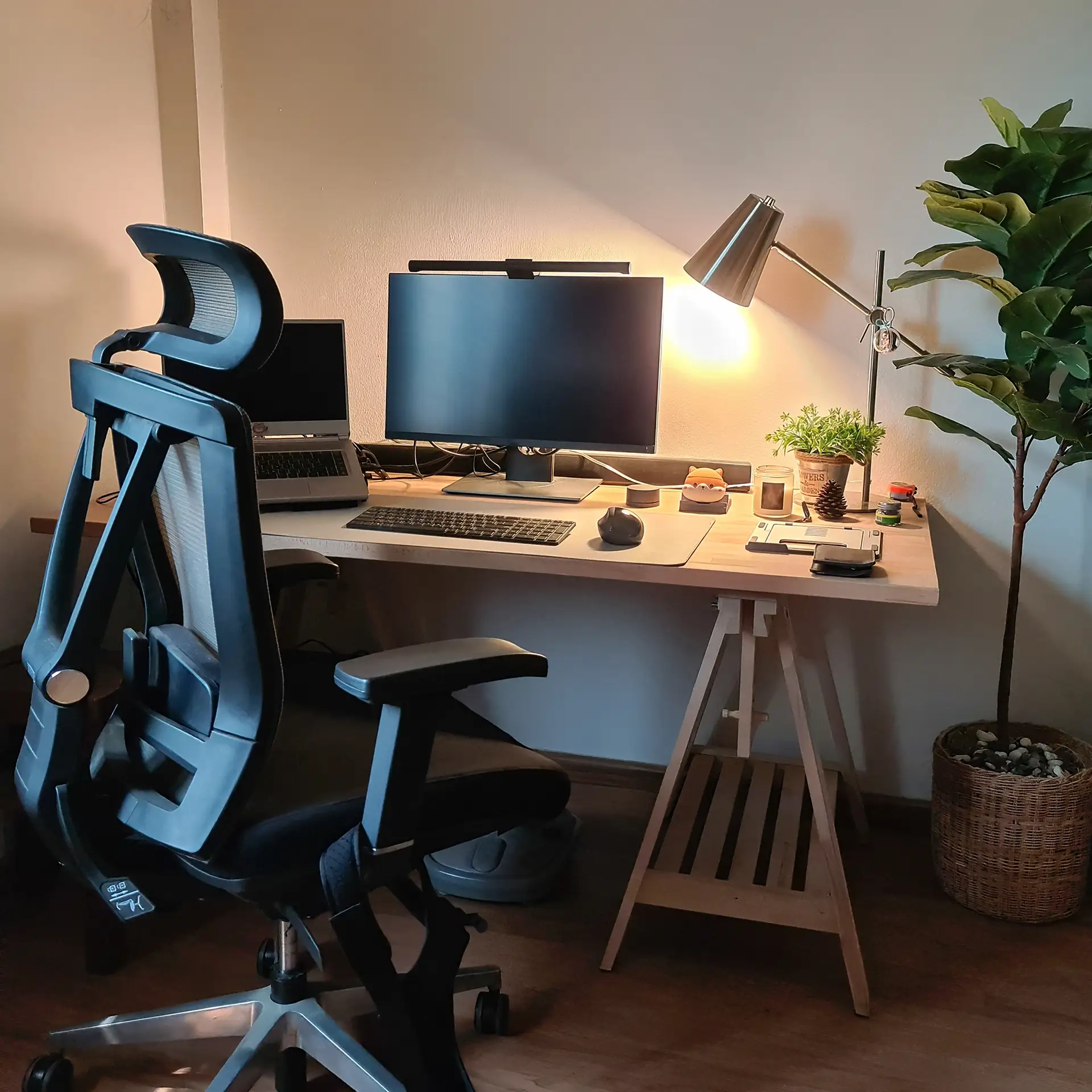 Working corner with monitor, laptop, wooden desk, ergonomic chair, and decorative objects