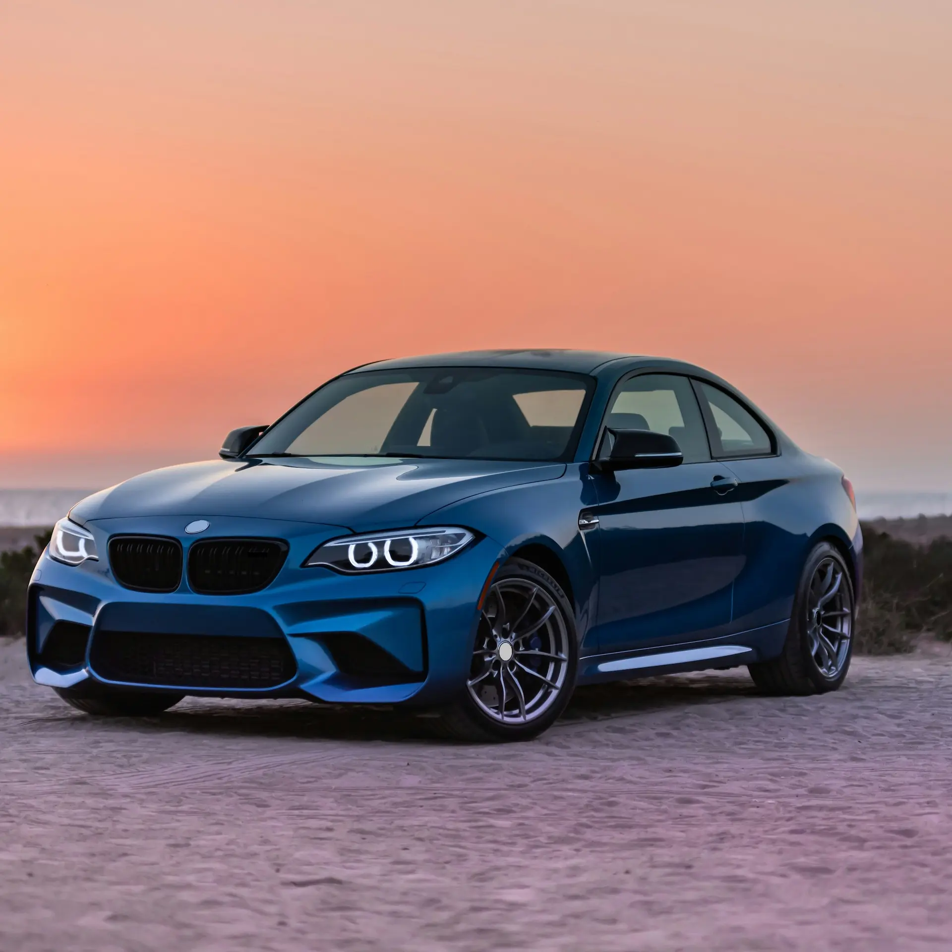 Modern blue BMW sedan parked three quarter front angle an sunset