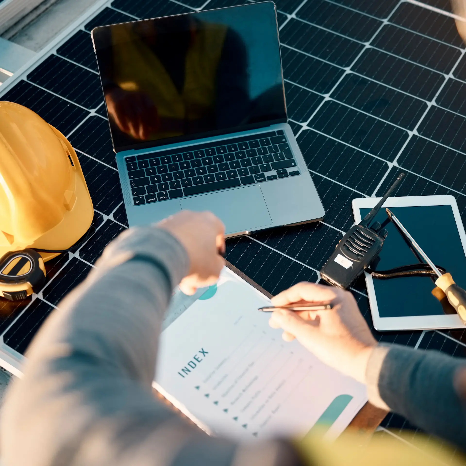 A Solar System Engineer is making notes while checking a commercial solar system installation.