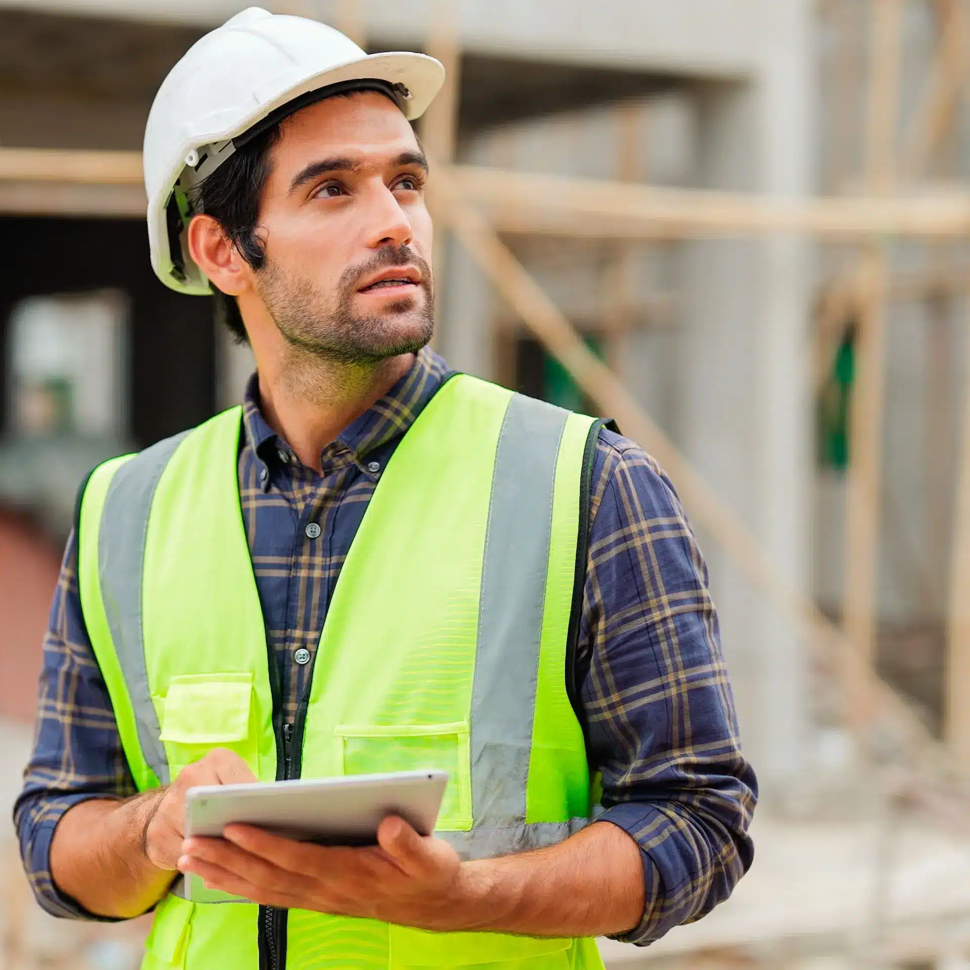 A construction foreman is holding an iPad as he calculates crane finance on a building site.