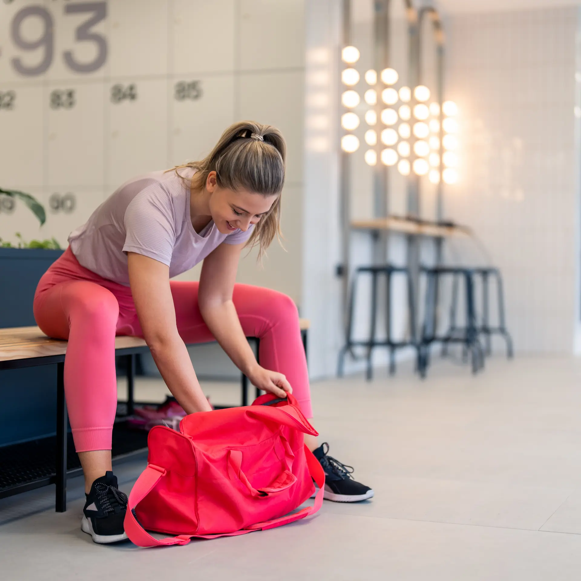 A young woman packing gear into her duffle bag after a good workout at the gym.