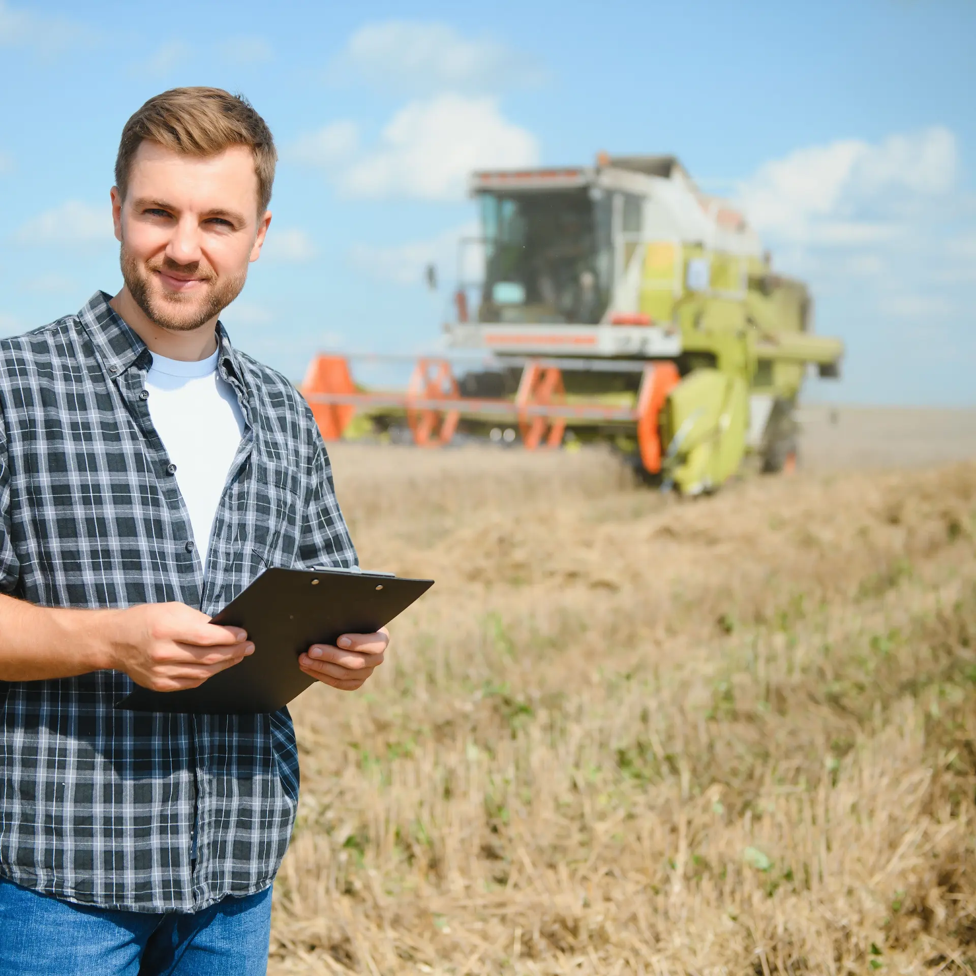 You farmer holding an iPad is working out costs of the current harvest and considers replacing old failing equipment.