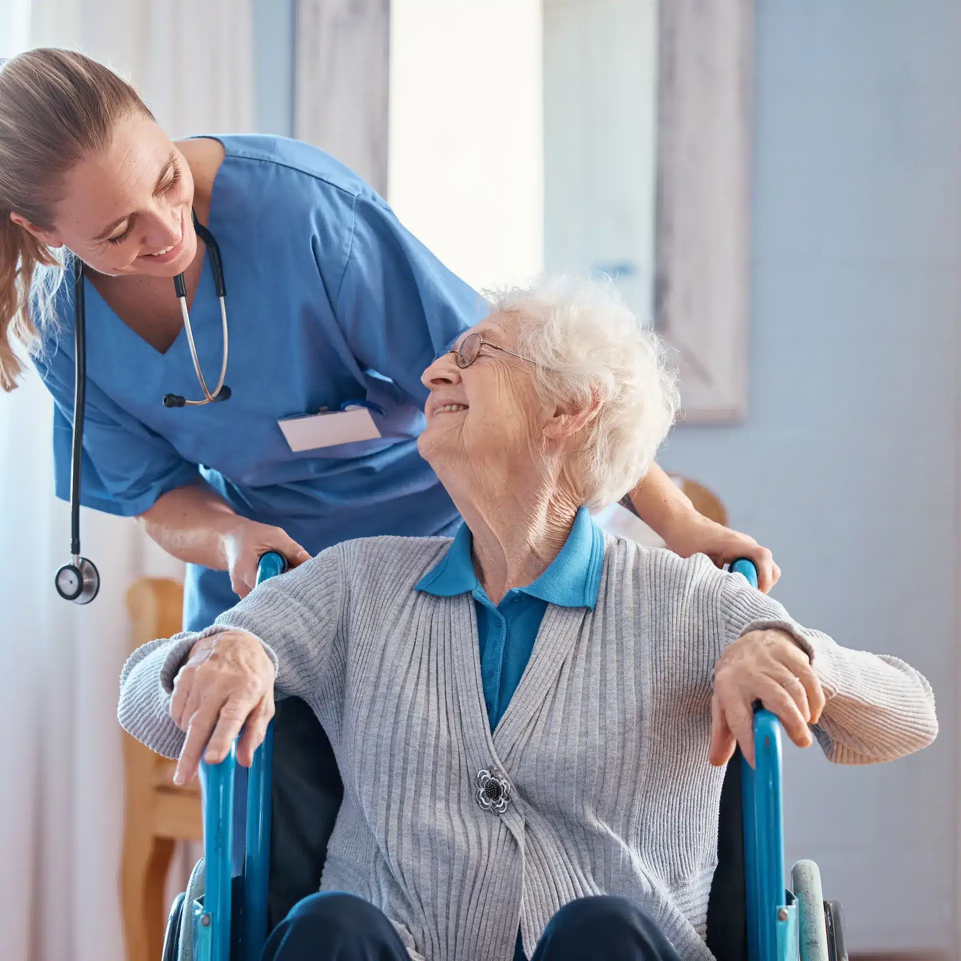 A health care nurse attending to an elderly lady patient in a wheel chair in an aged care facility.