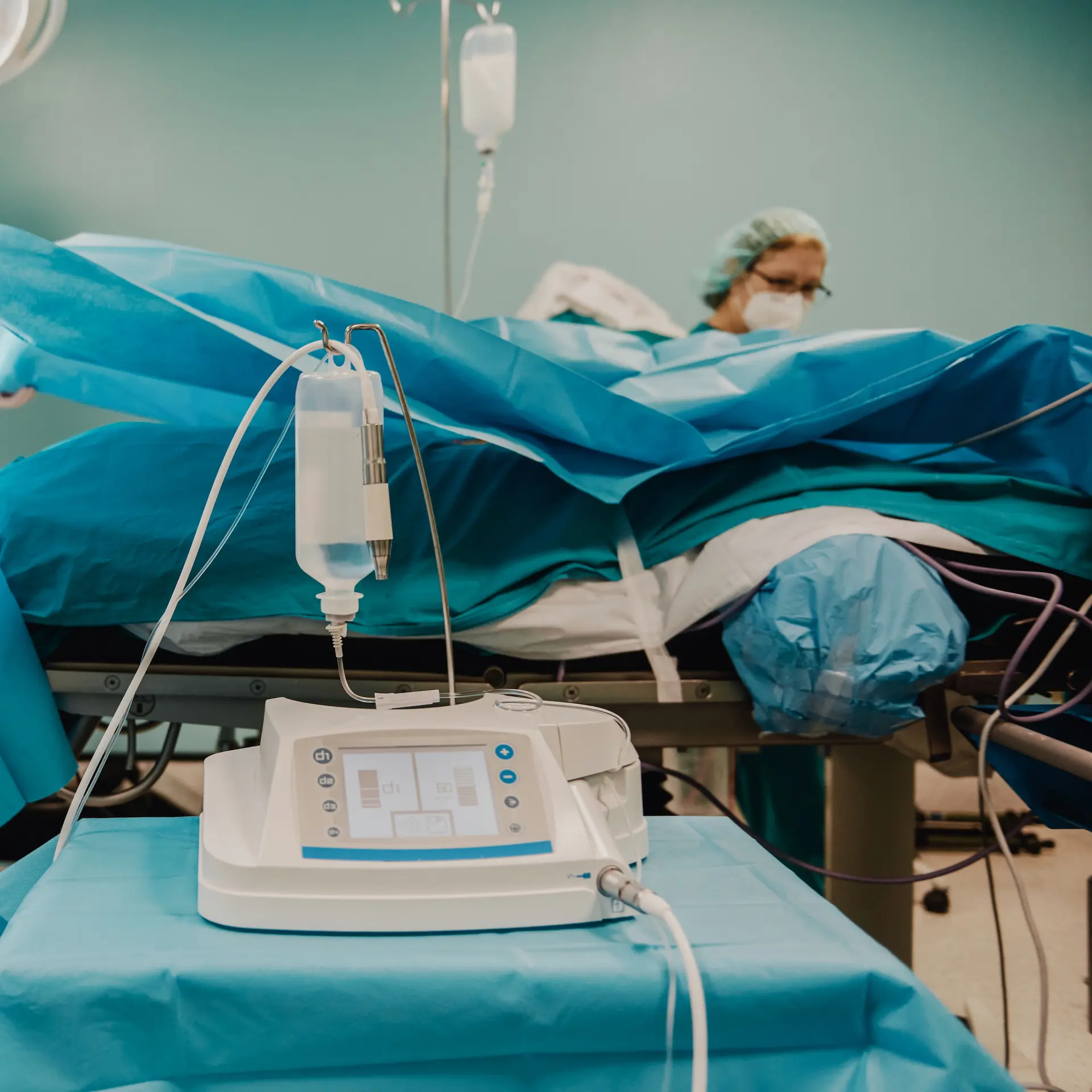 A medical team preparing for a surgical procedure in the background, with medical equipment on a trolly table in the foreground.