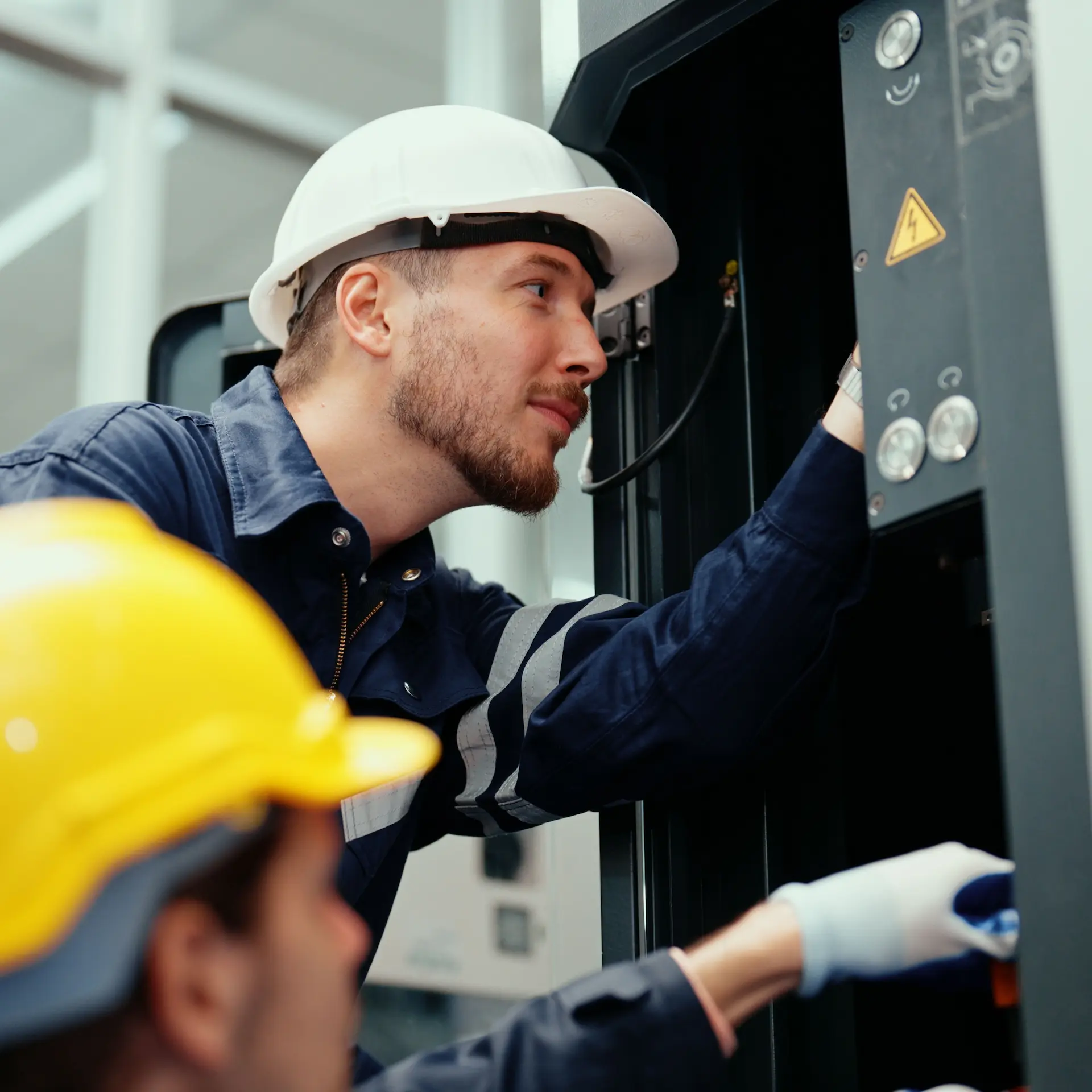 Electrical technicians working on industrial factory machinery.