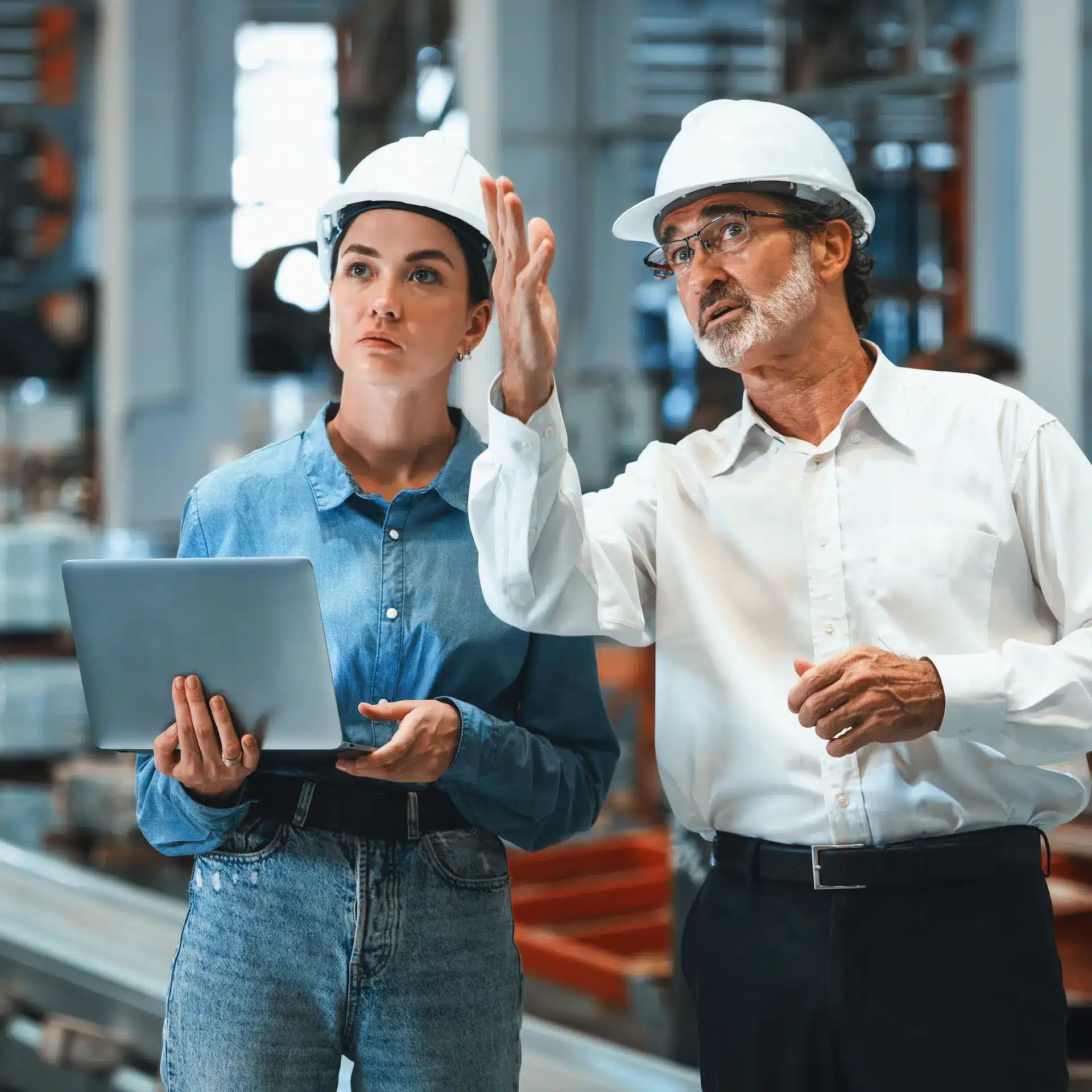 An industrial factory manager discusses machinery upgrades with his production supervisor.