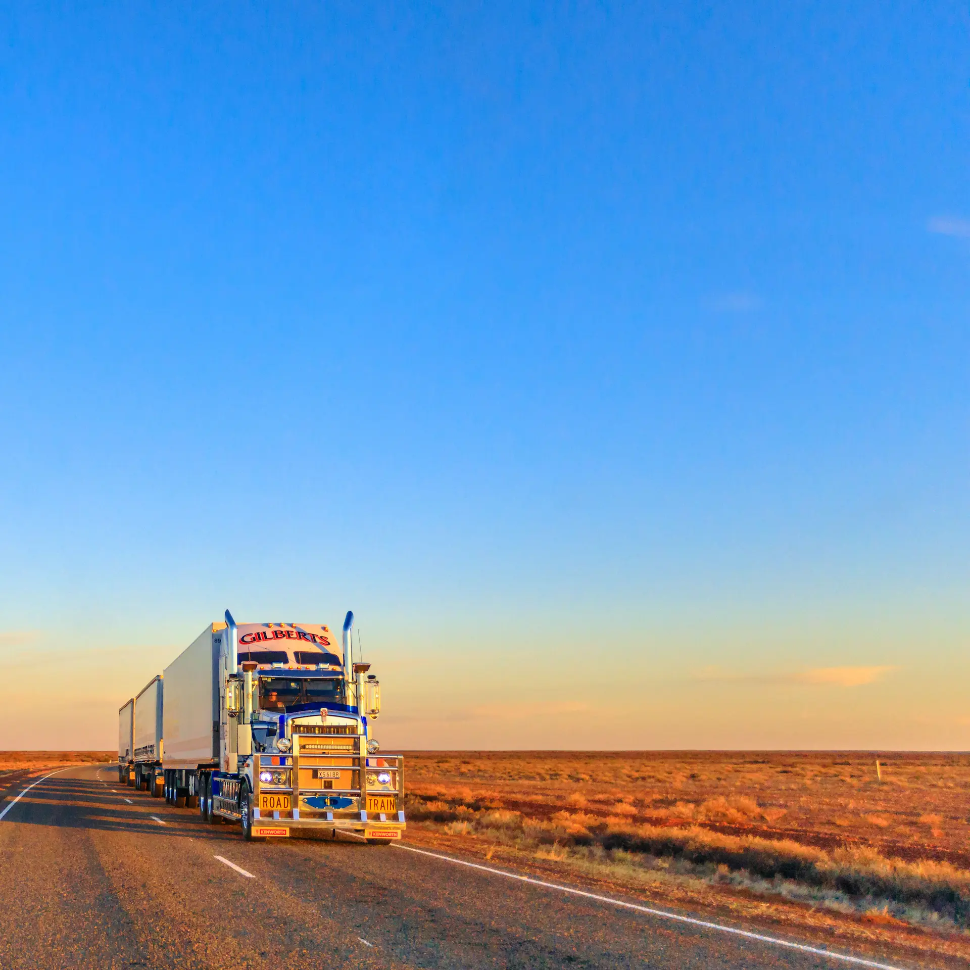 A Kenworth road train cruising down the highway in the Australian outback.