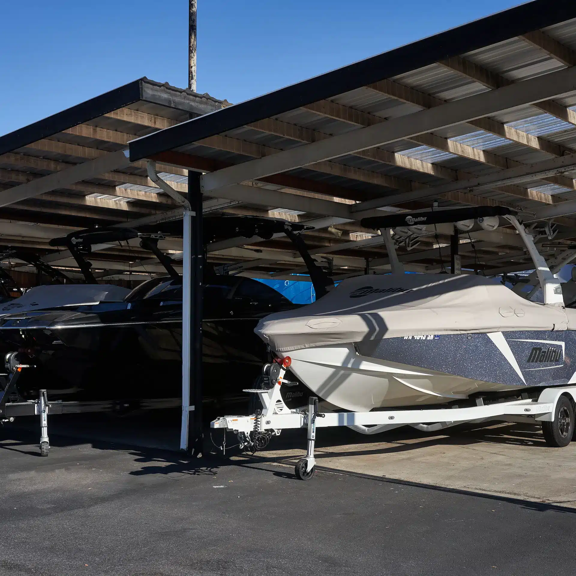 A row of modern boats parked on their trailers under over at a boat storage facility.