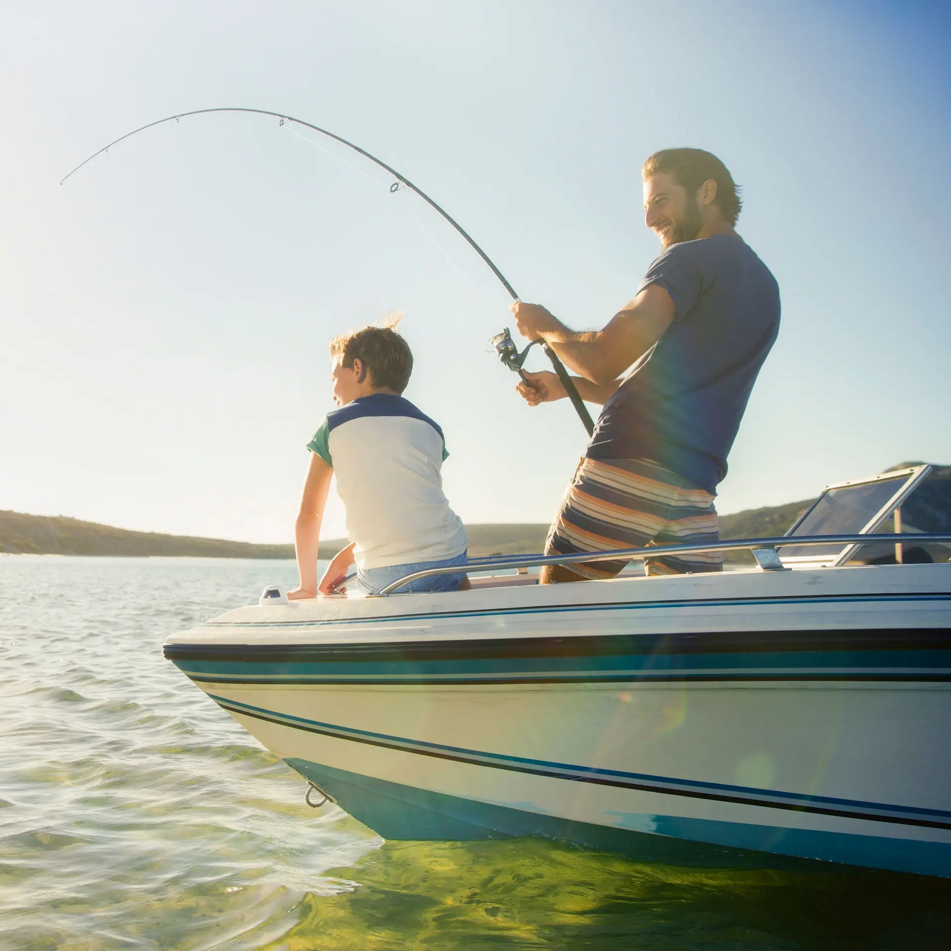 Father and son fishing off their small private boat in calm water.