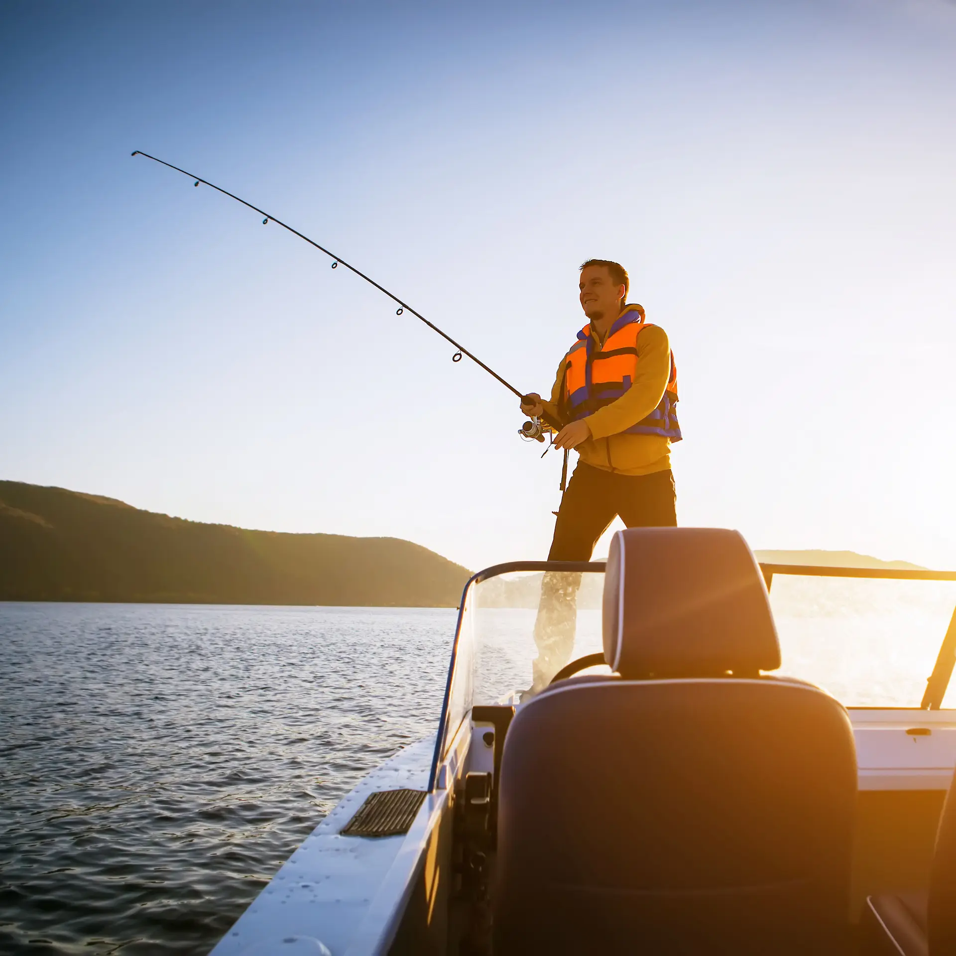 A man fishing from his small boat in beautiful sunny weather on flat water.
