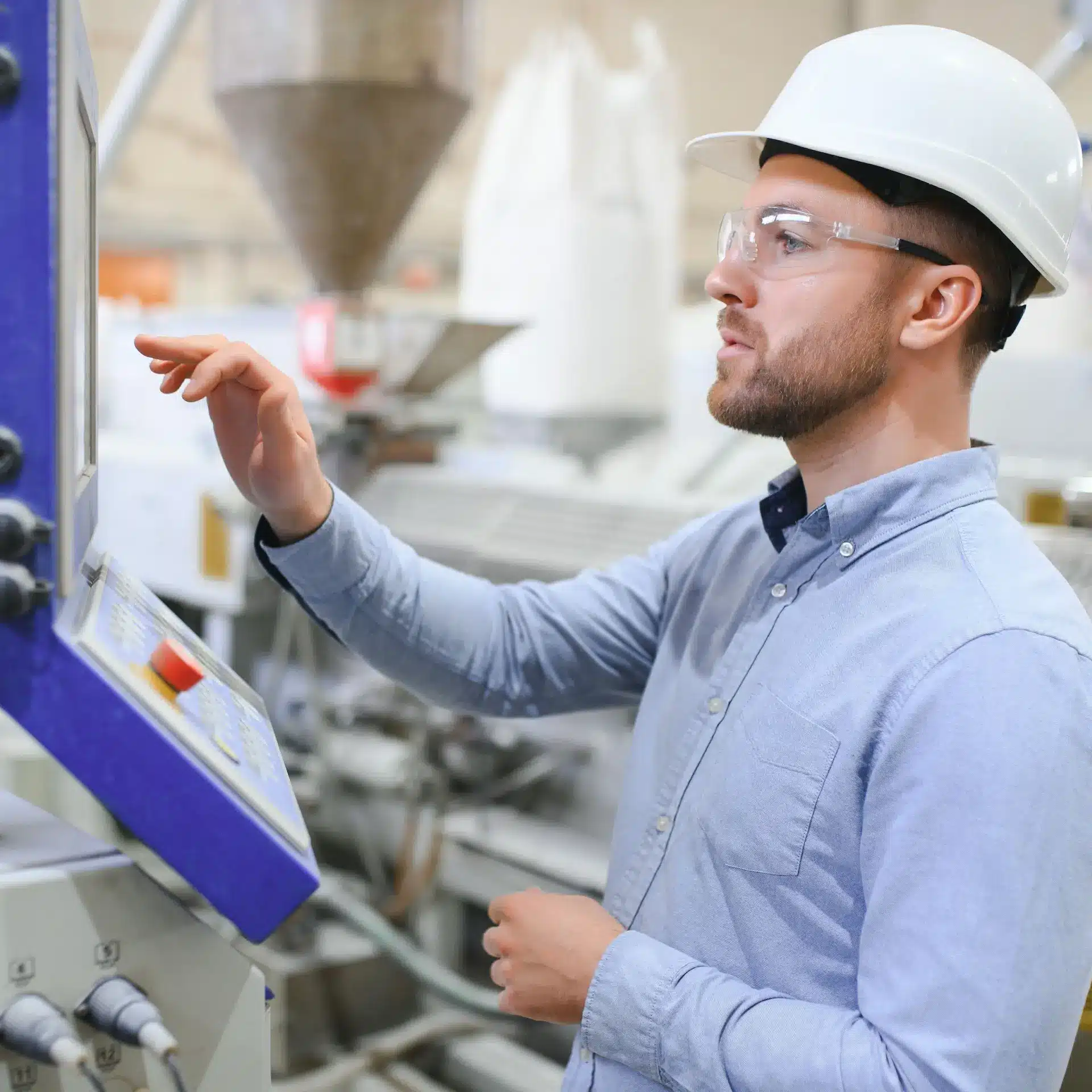 A manufacturing process supervisor checking machine function at a control console in a manufacturing plant.