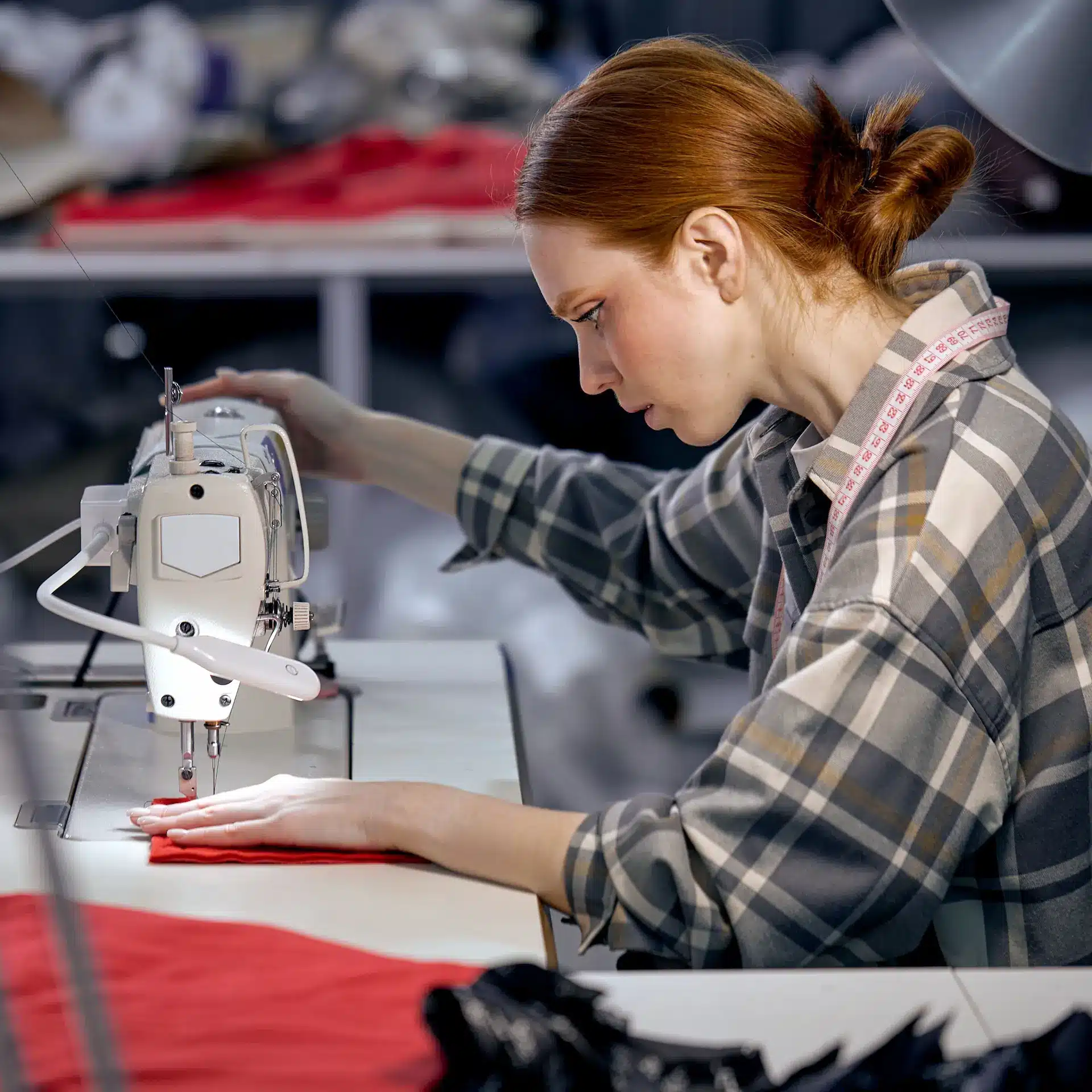 A seamstress is using a sewing machine to manufacture a garment.