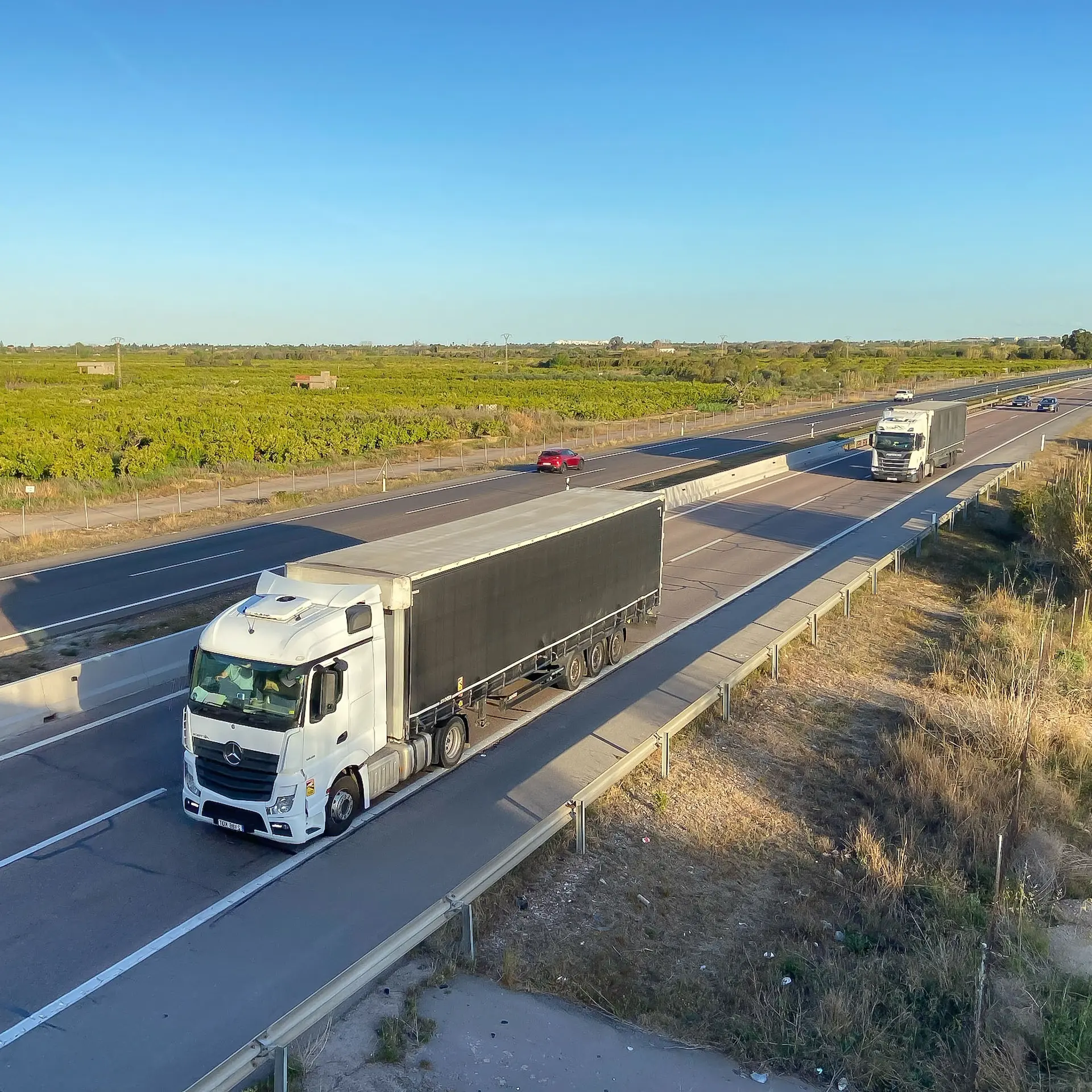 A Mercedes prime mover driving down the highway with a semi trailer.