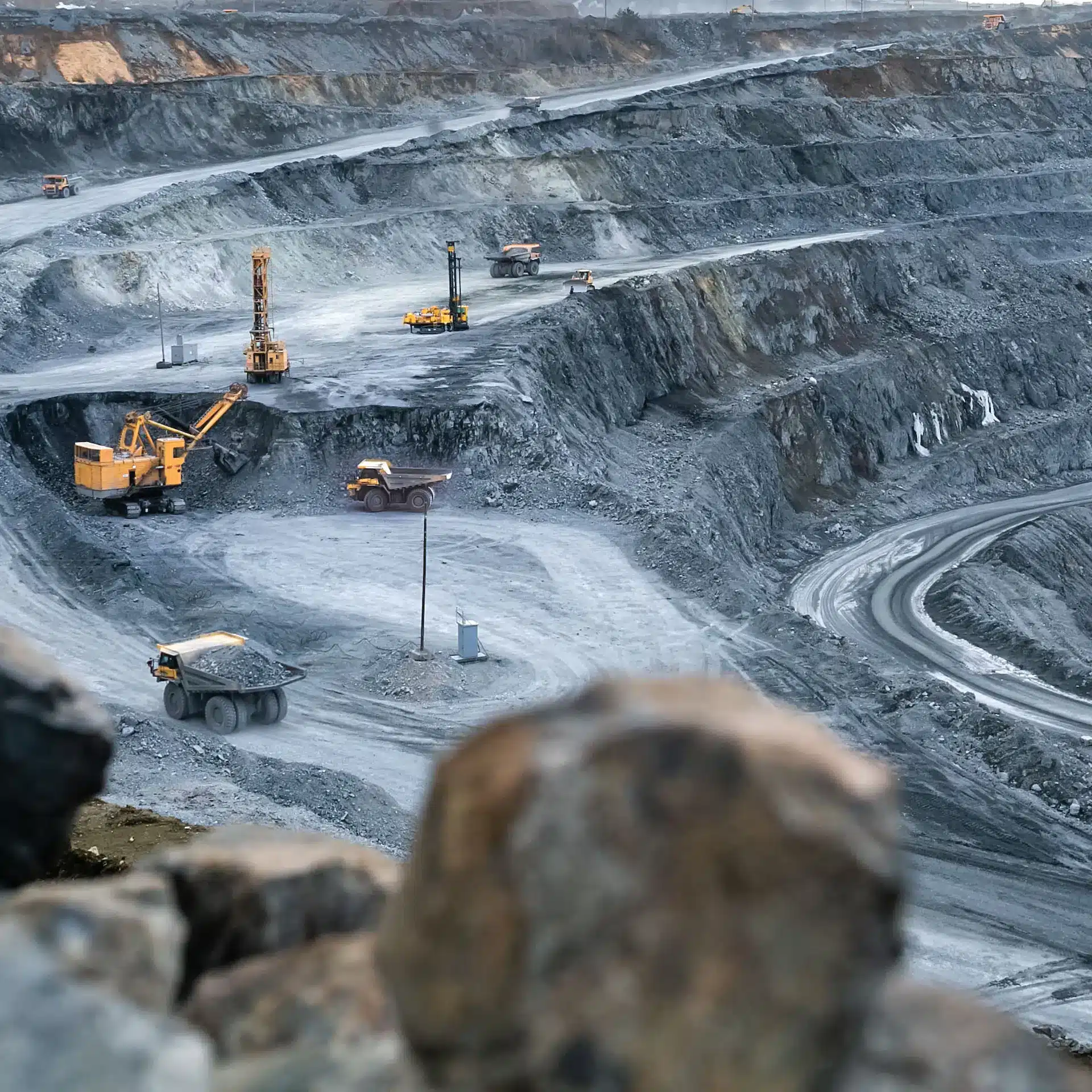 An open pit mine with several machines working in the distance.