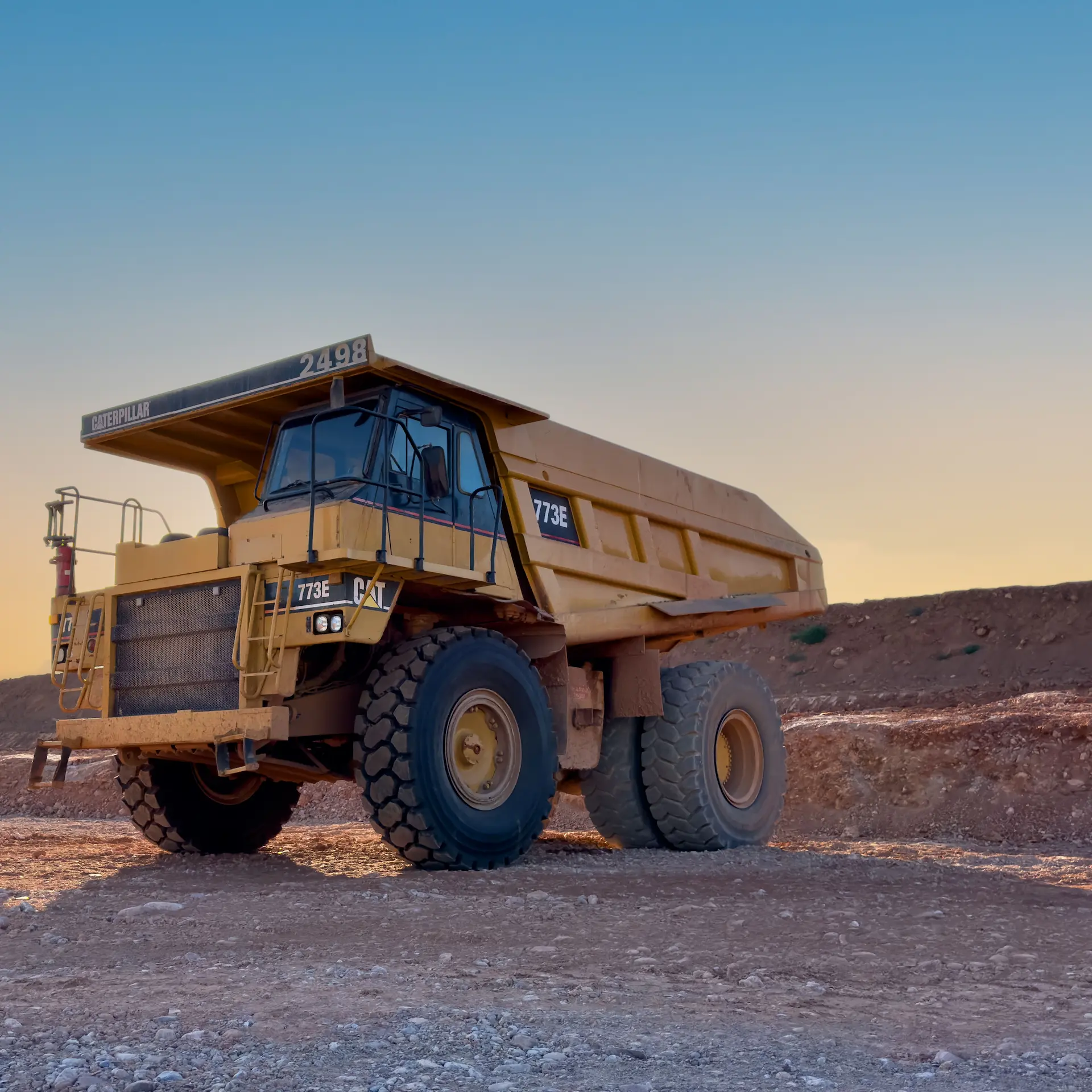 A large mining dump truck parked at a mining site during early morning.
