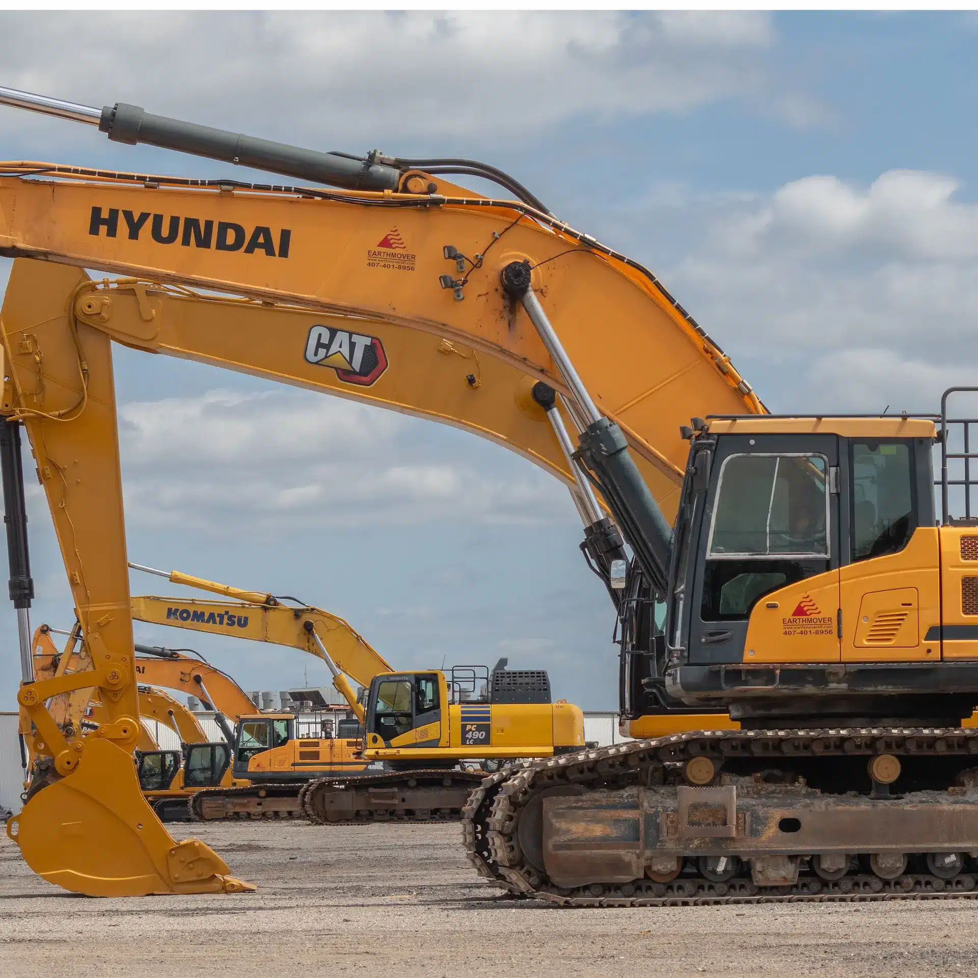 A row of large excavators at an earthmoving auction ready for inspection.