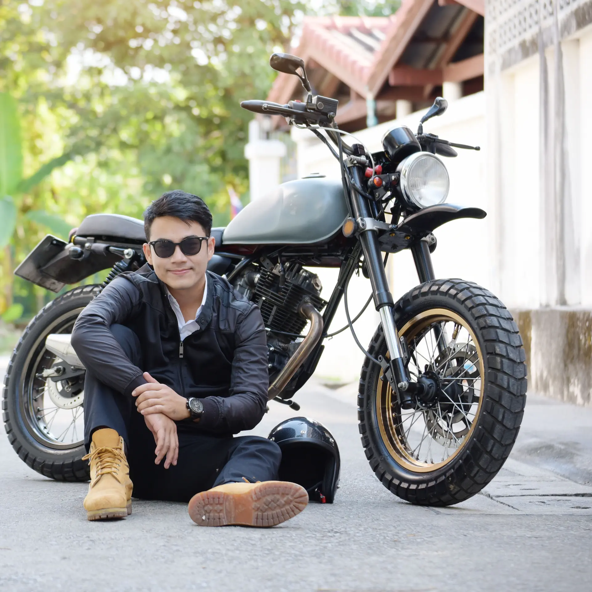 A motorcyclist sitting on the ground in front of his parked motorbike.