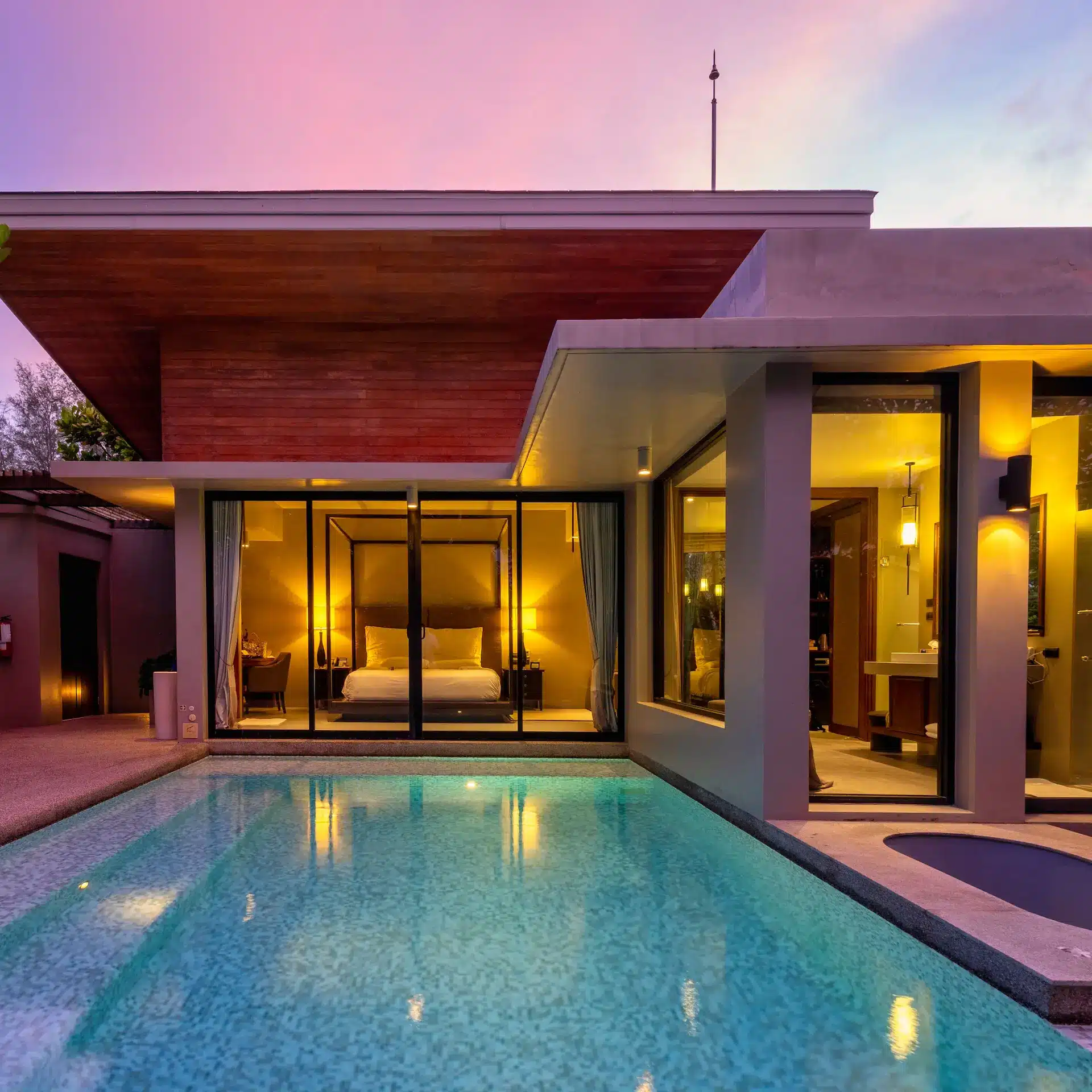 A modern home with a pool nicely lit at dusk.