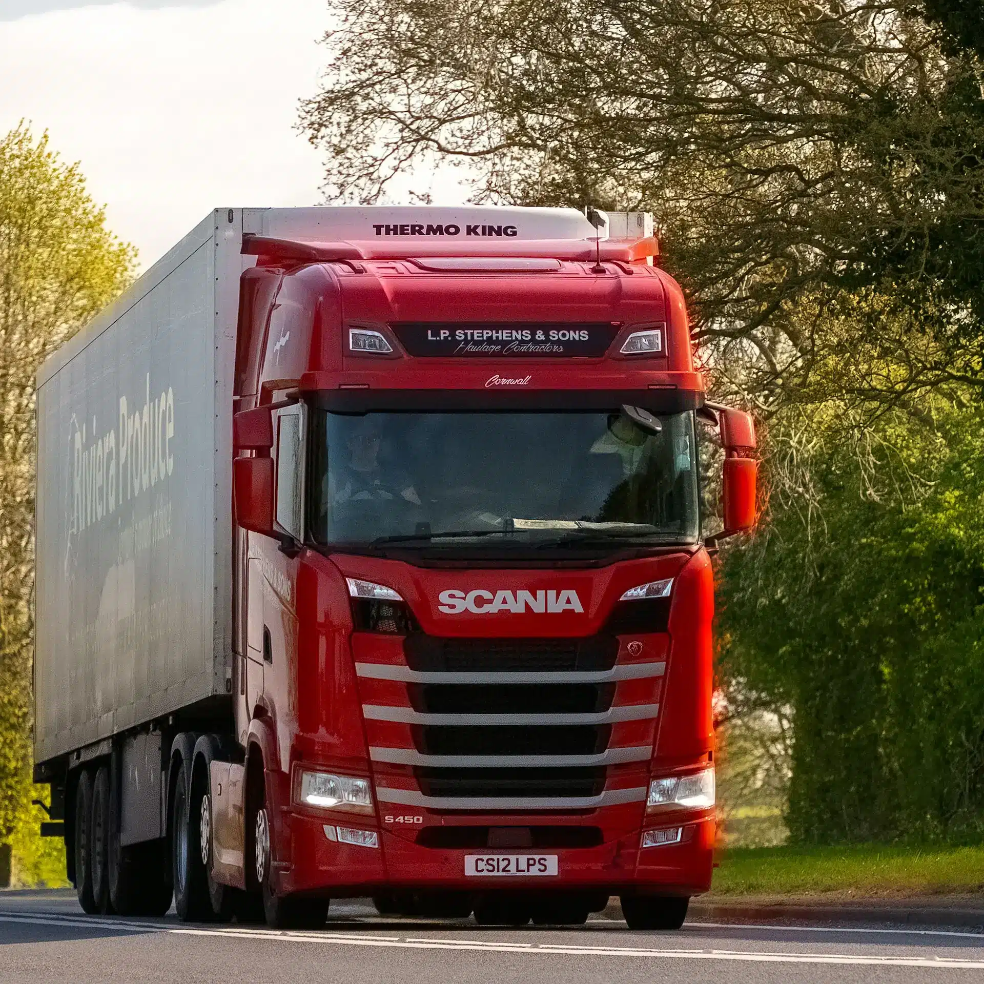 A red Scania truck hauling a semi trailer on a country road.