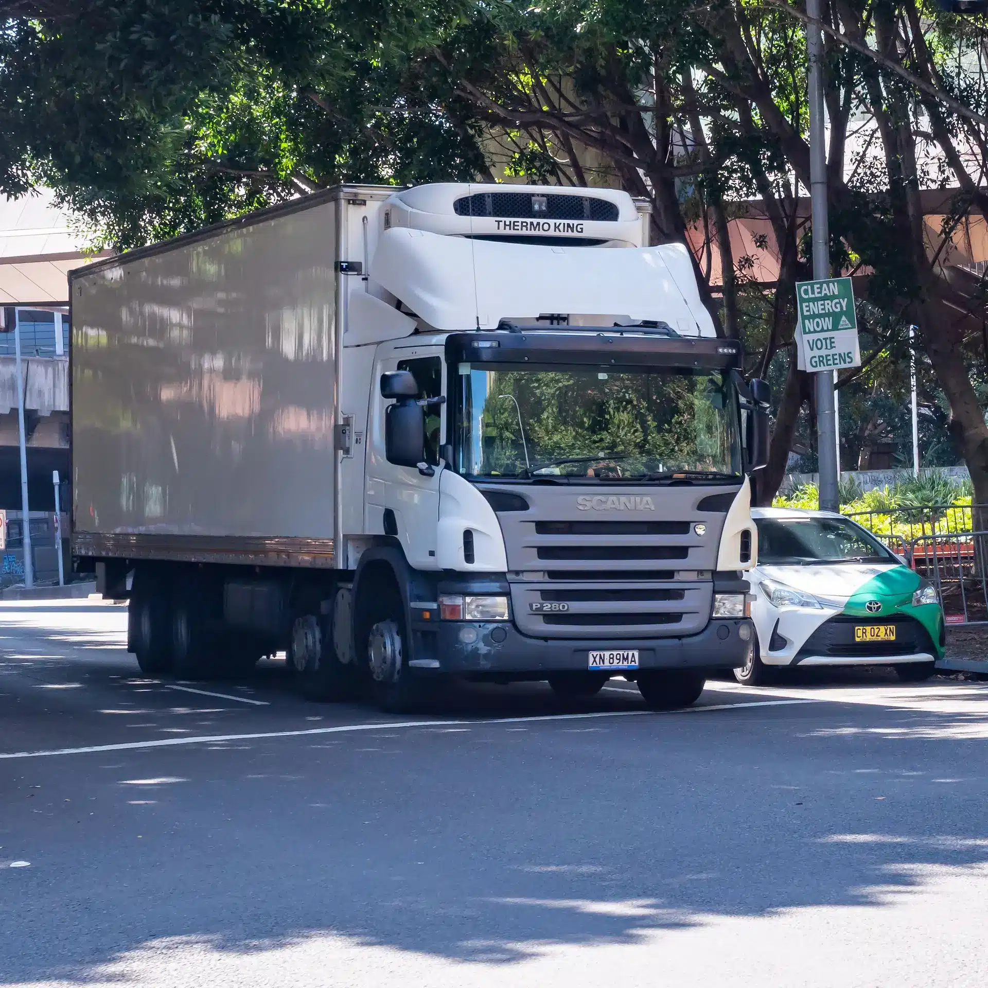 A white Scania truck in Sydney traffic with a rigid body.