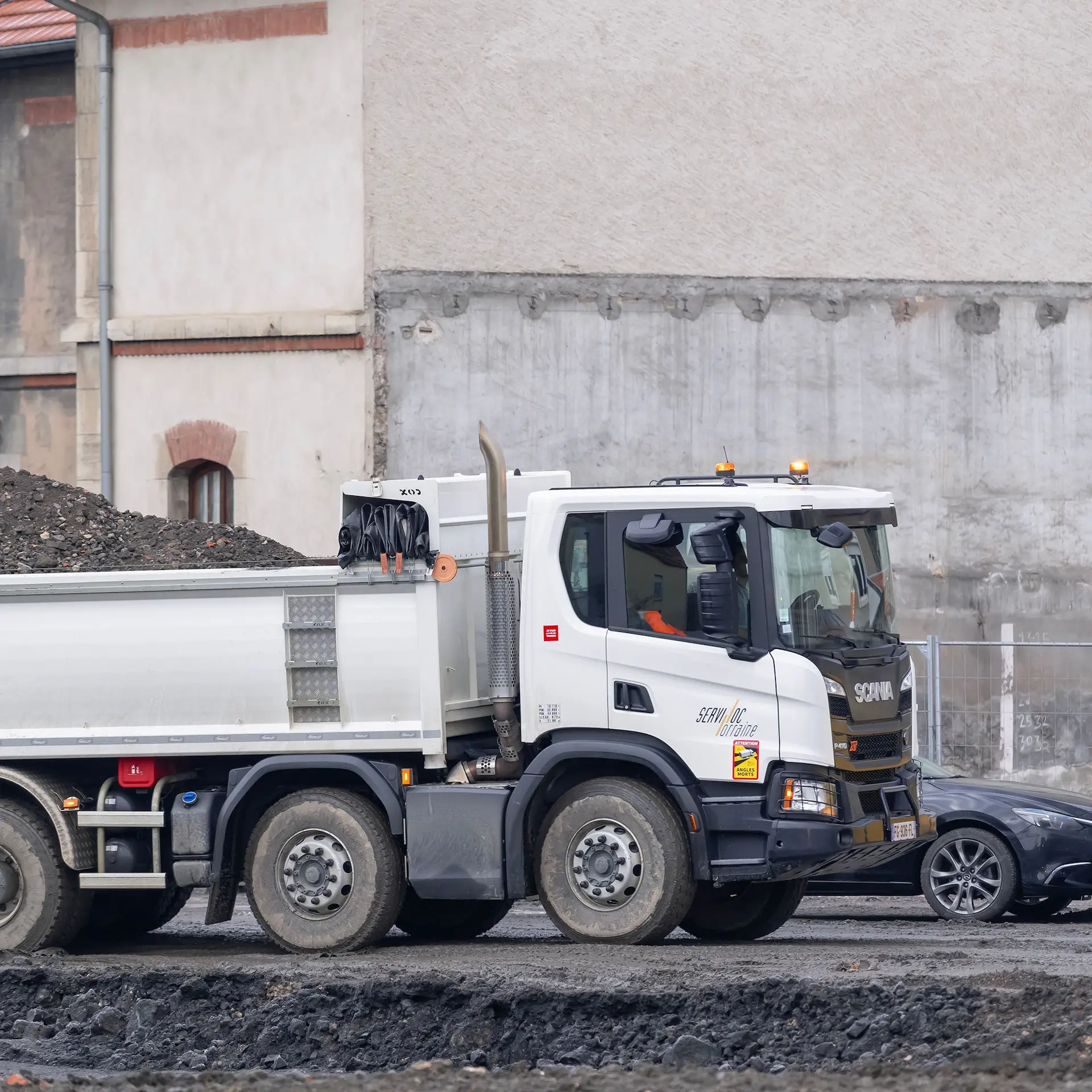 A white Scania dump truck working on a construction site.