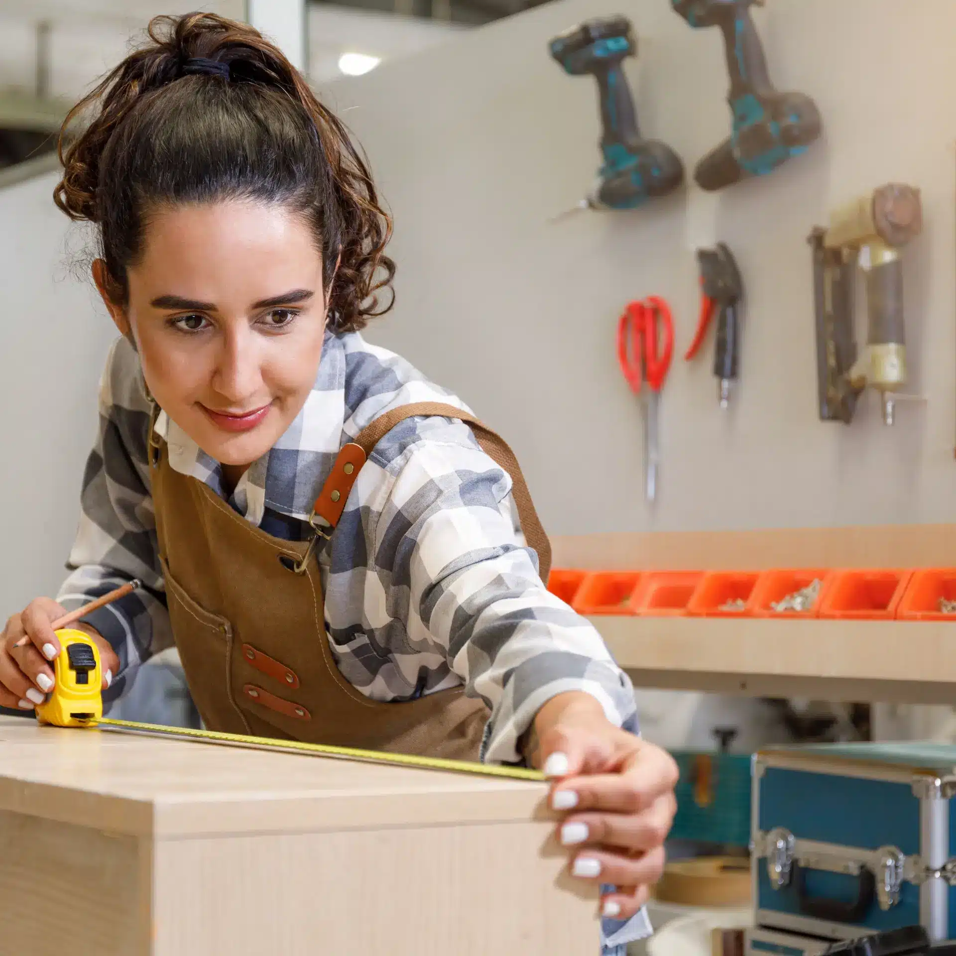 A young woman working on a handcrafted furniture piece in her start-up woodworking shop.