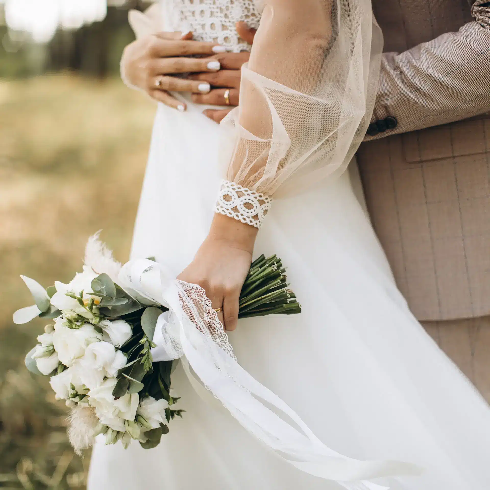 A newly married couple on their wedding day standing, with the bride's gown and bouquet featured.