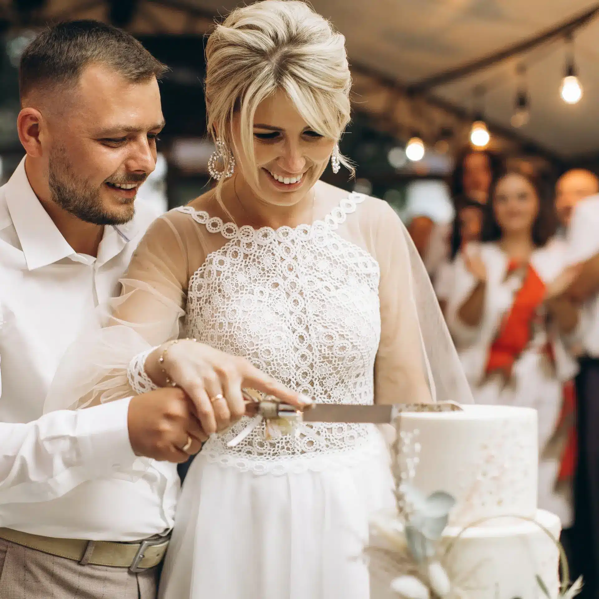 A newly married couple at their wedding reception cutting the wedding cake together in a marque