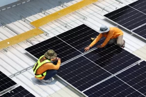 Two professional solar technicians install solar panels on the roof of a commercial building after the property owners used a solar loan to reduce energy costs sooner with minimal upfront investment