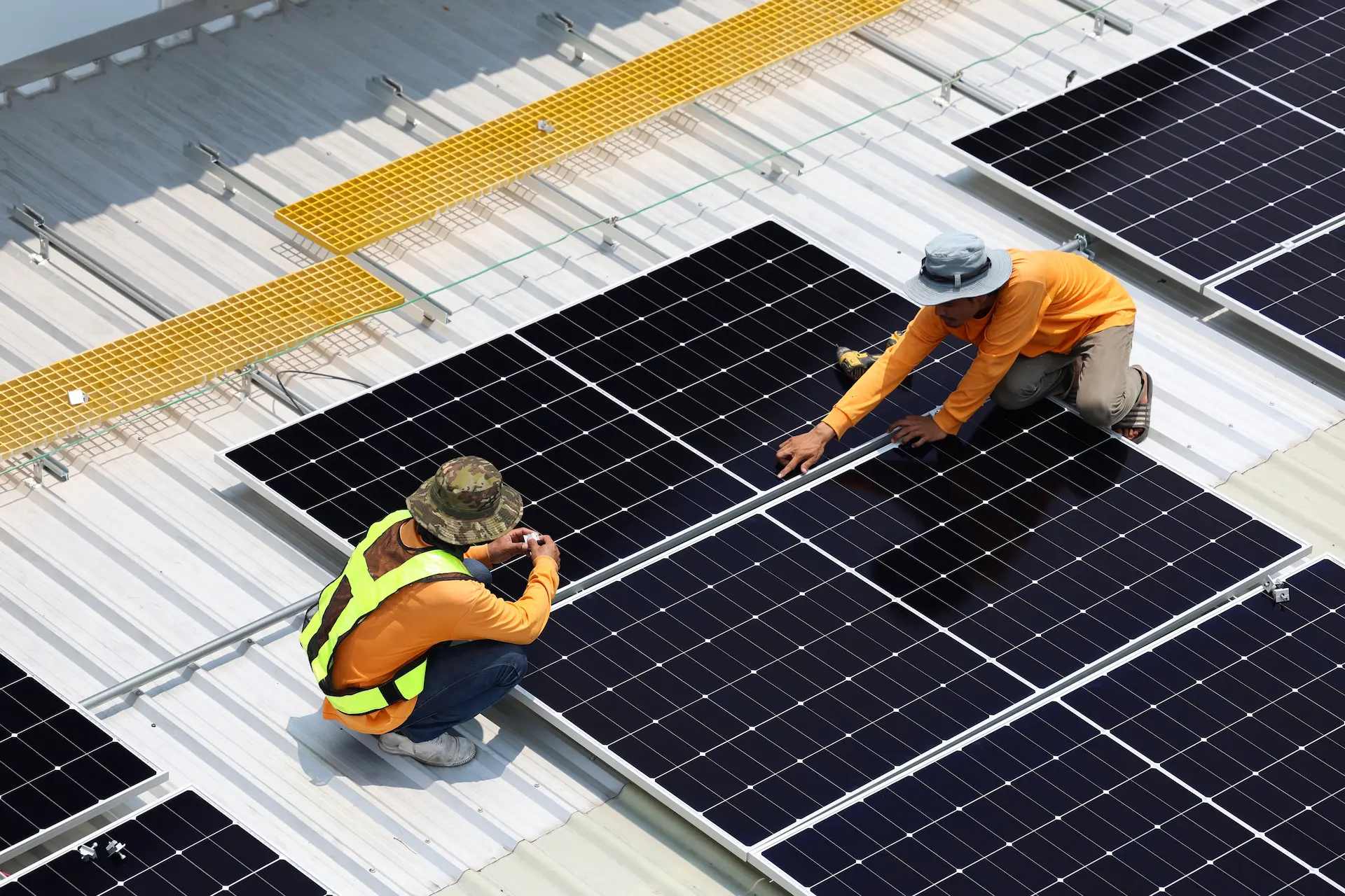 Two professional solar technicians install solar panels on the roof of a commercial building after the property owners used a solar loan to reduce energy costs sooner with minimal upfront investment