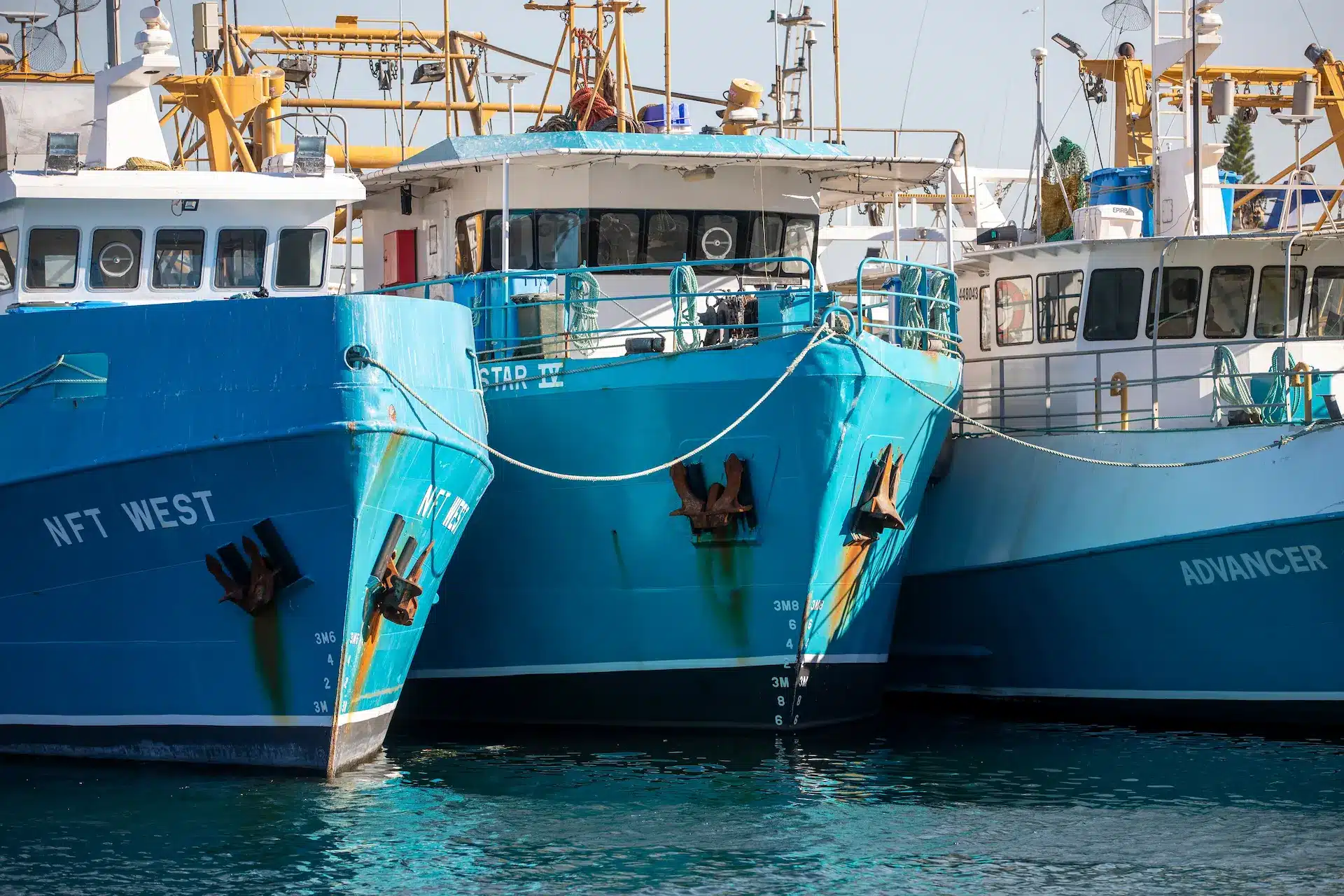 Several blue commercial trawlers lined up at the doc in Perth Australia.